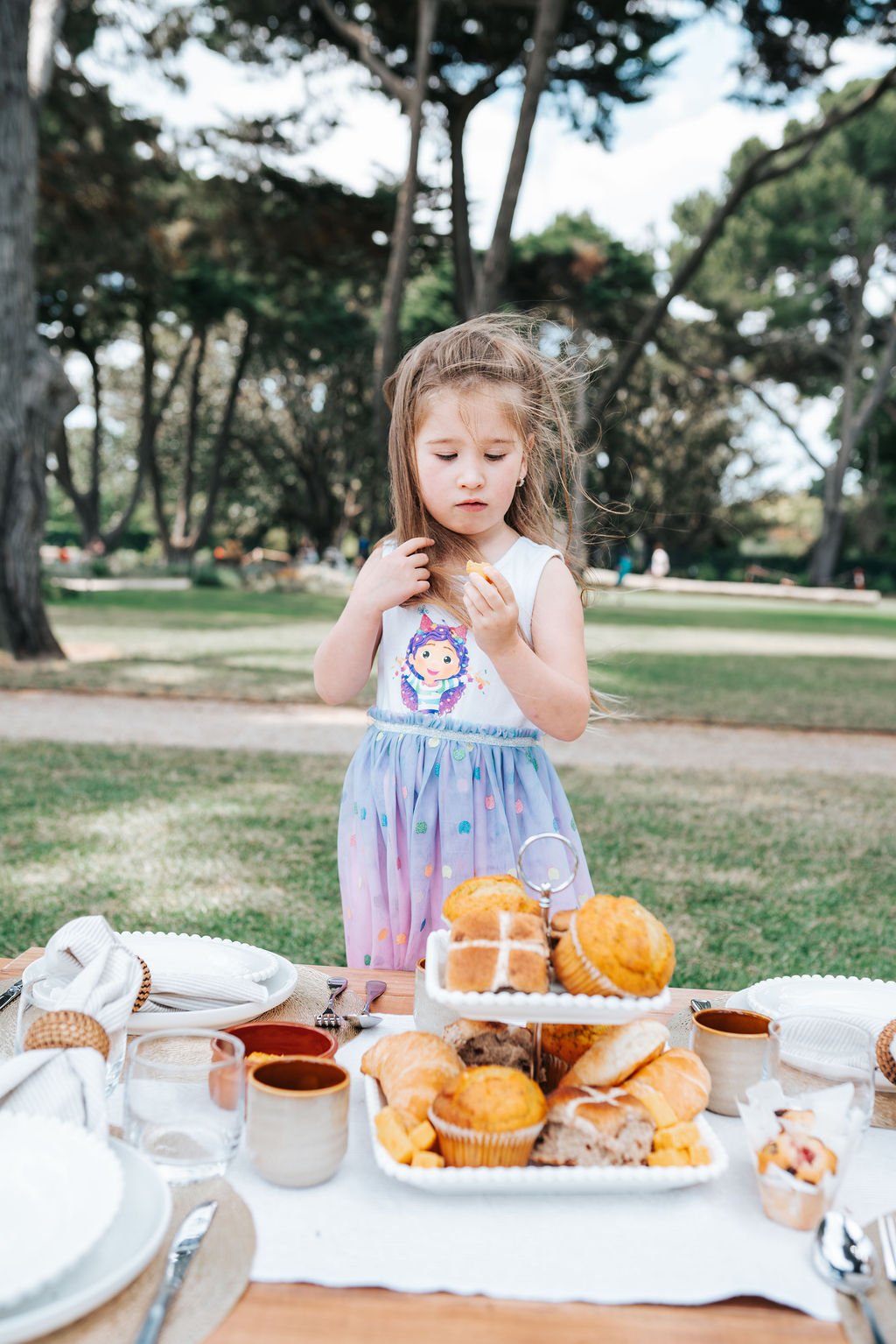 Family-friendly outdoor picnic setting with artisan baked goods, elegant styling, and relaxed park surroundings.