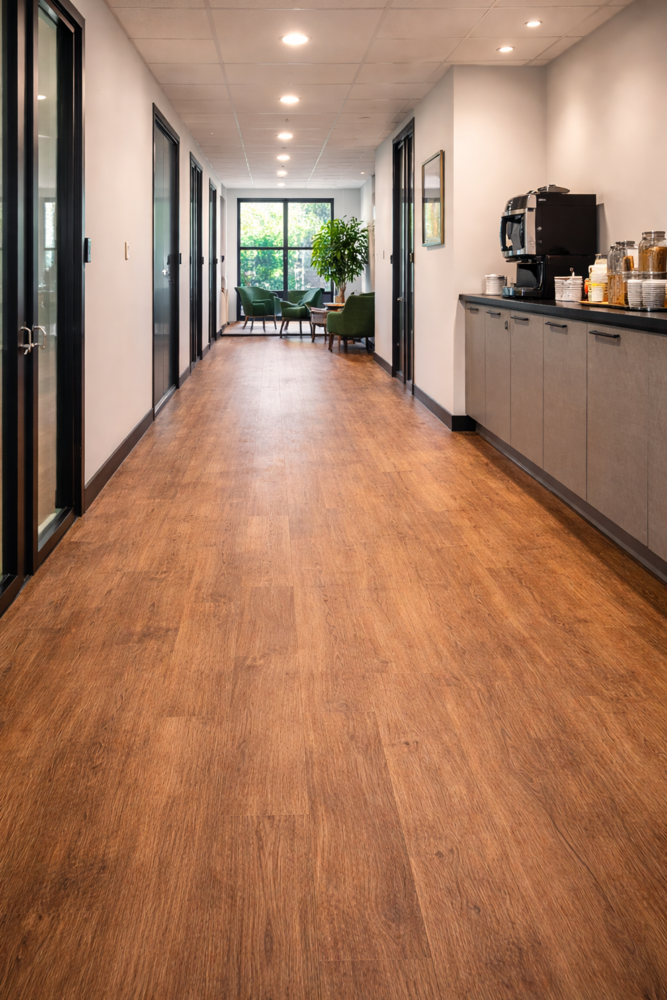 Wood-effect luxury vinyl tile (LVT) flooring installed in a modern office corridor with breakout seating area, providing durable, easy-to-maintain flooring for high-traffic commercial environments in Surrey and South West London