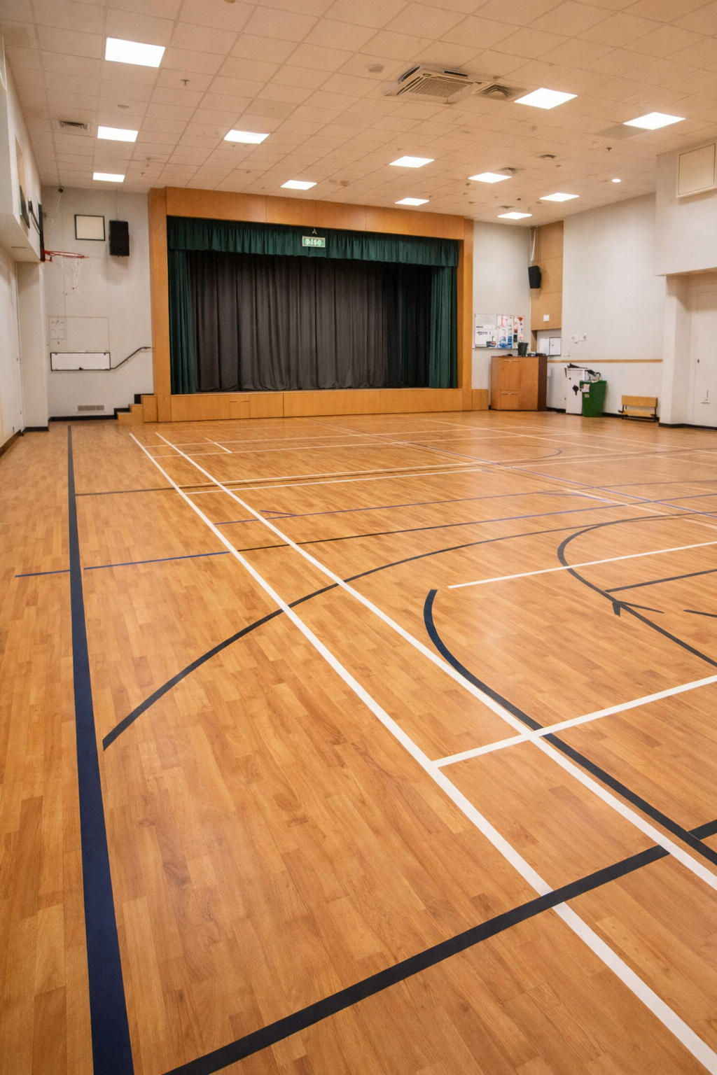 Wood effect sports vinyl flooring installed in a large school assembly hall used for sports and events