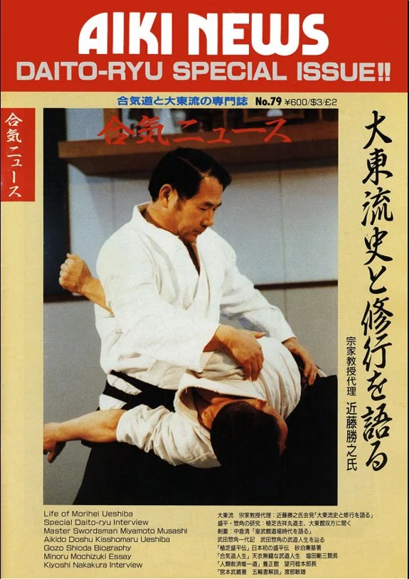 A magazine cover titled 'AIKI NEWS' featuring a martial arts demonstration where a man in a white gi practices a move on another person lying on the floor. The cover includes Japanese and English text, with additional articles and interviews listed at the bottom.