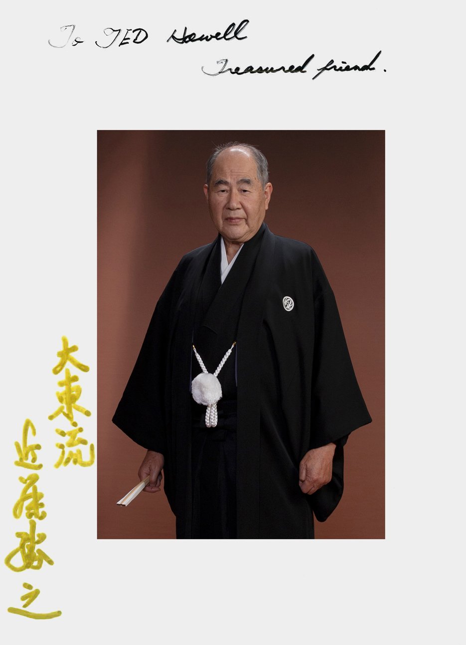 A portrait of an elderly Japanese man dressed in traditional black robes, holding a folding fan, with handwritten notes at the top reading "To TED Howell, Treasured friend," and Japanese characters in yellow at the bottom left.