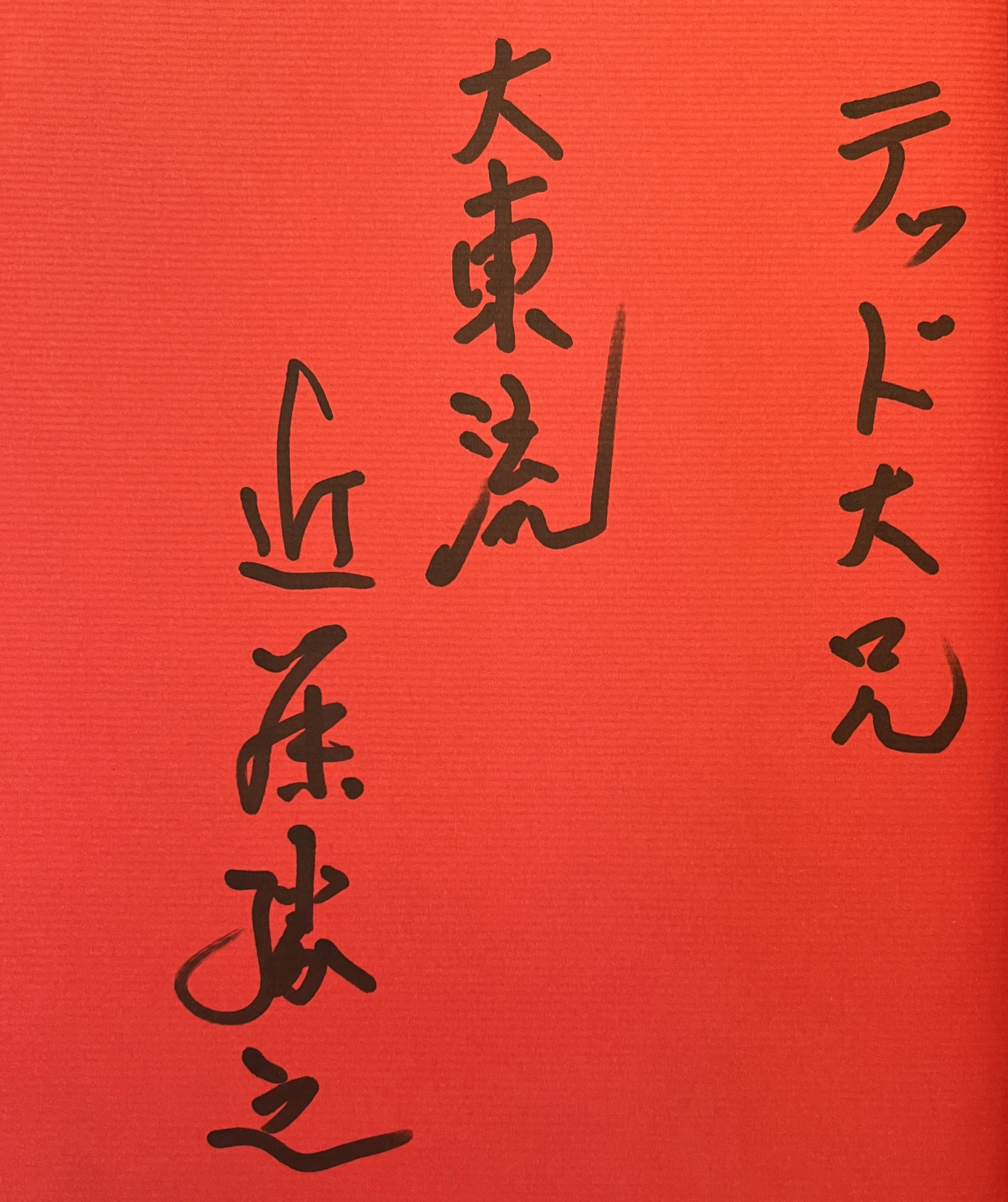 Close-up of red paper with black Japanese calligraphy writing.