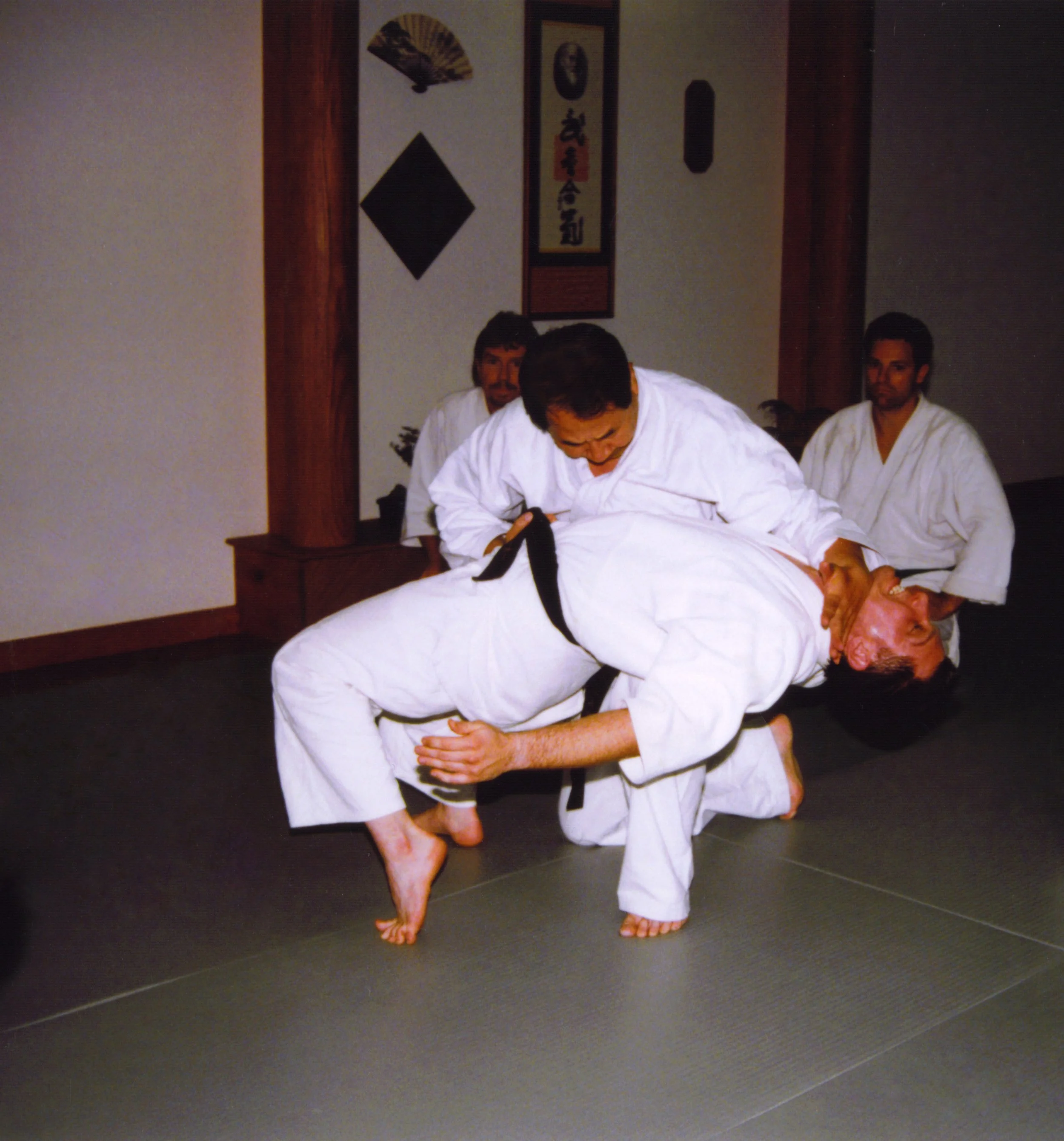 Two martial artists practicing judo techniques in a dojo.