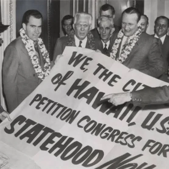 Richard Nixon and politicians wearing floral lei hold up a large petition roll reading "We, the Citizens of Hawaii... Petition Congress for Statehood Now".