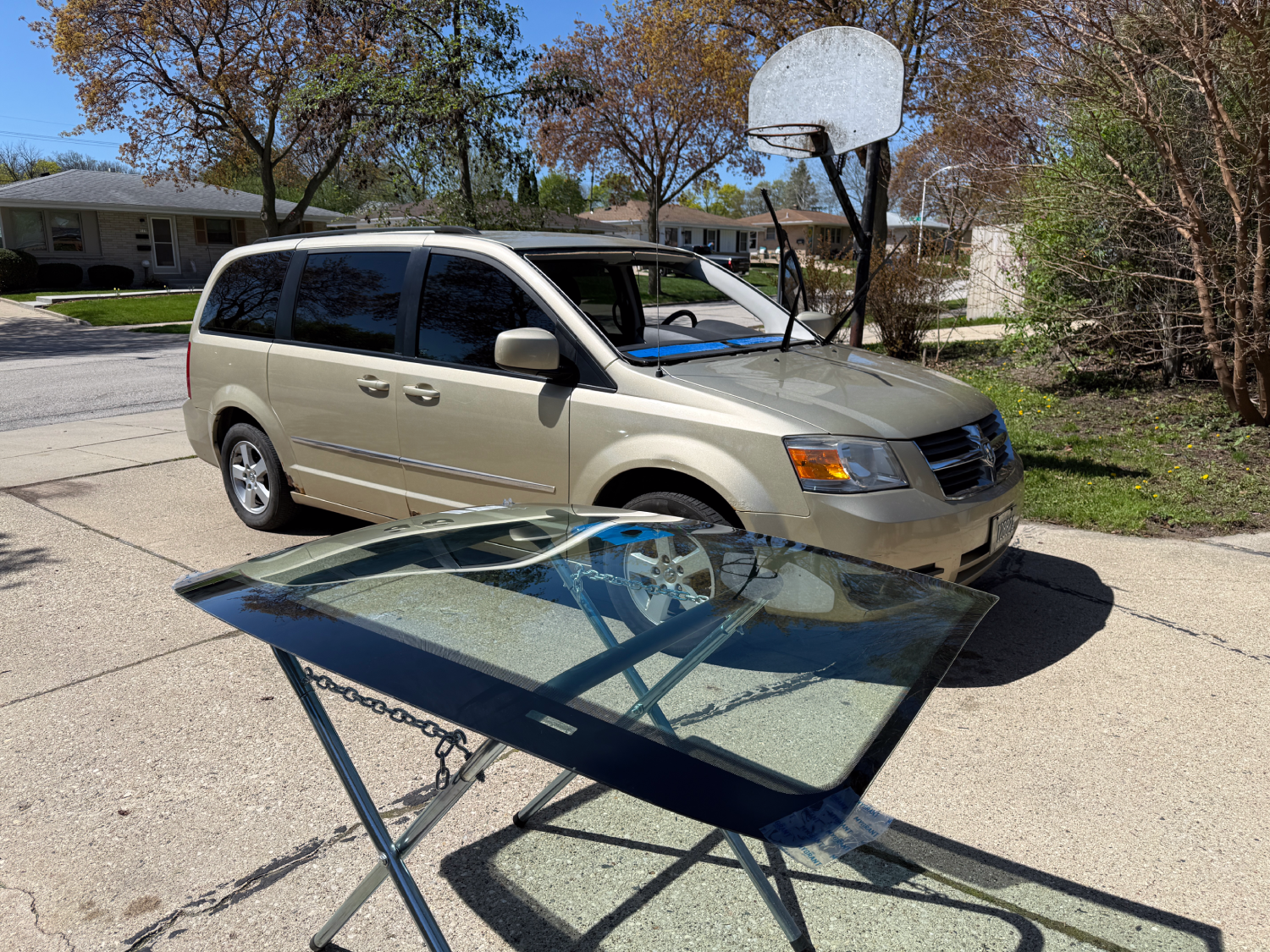 Mobile windshield replacement by OptiClear Auto Glass in Milwaukee, Wisconsin, with a new windshield prepared for installation on a Dodge Grand Caravan at the customer’s home.