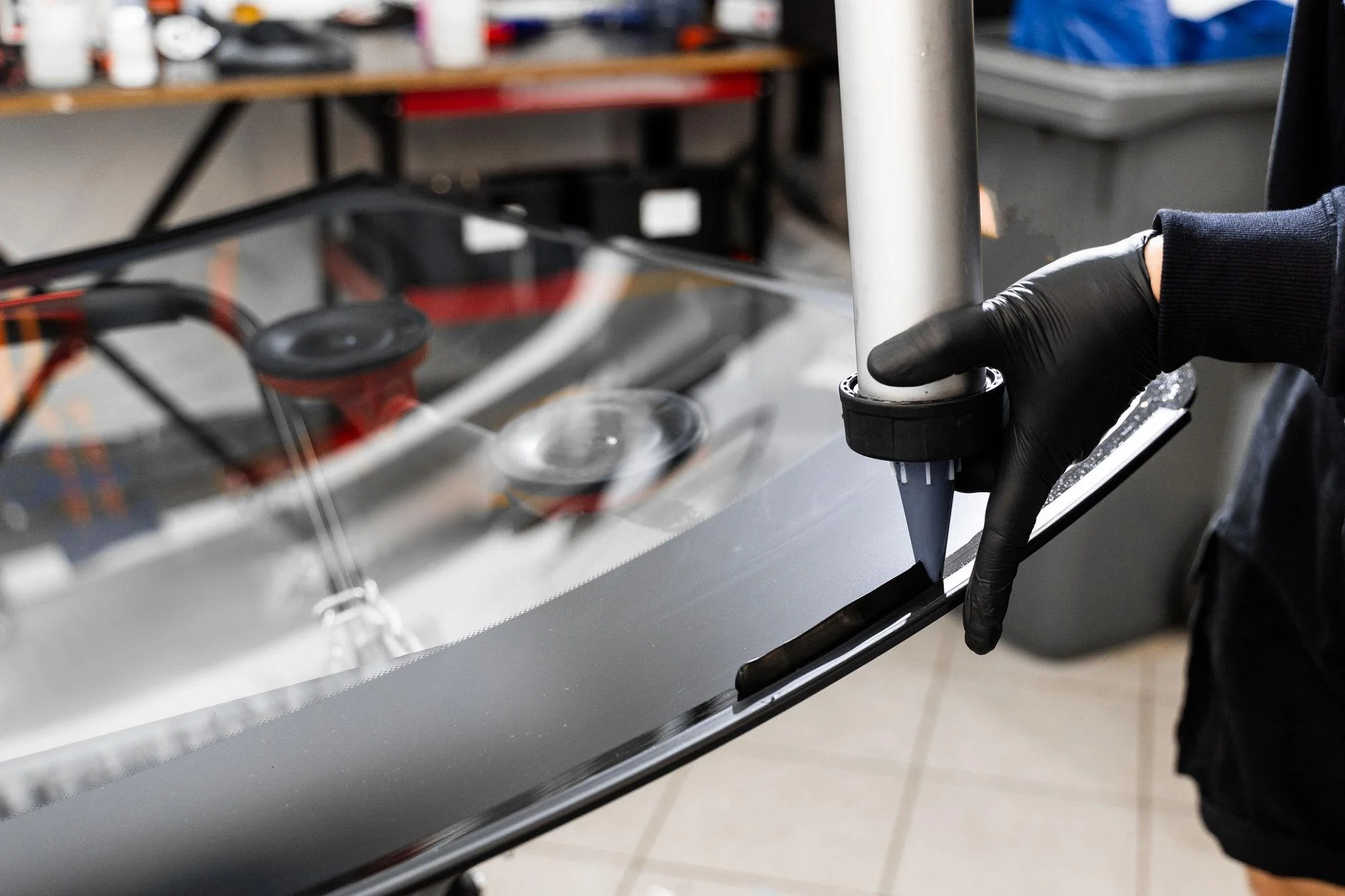 Urethane bead being laid on a brand new back windshield glass, ready for installation.