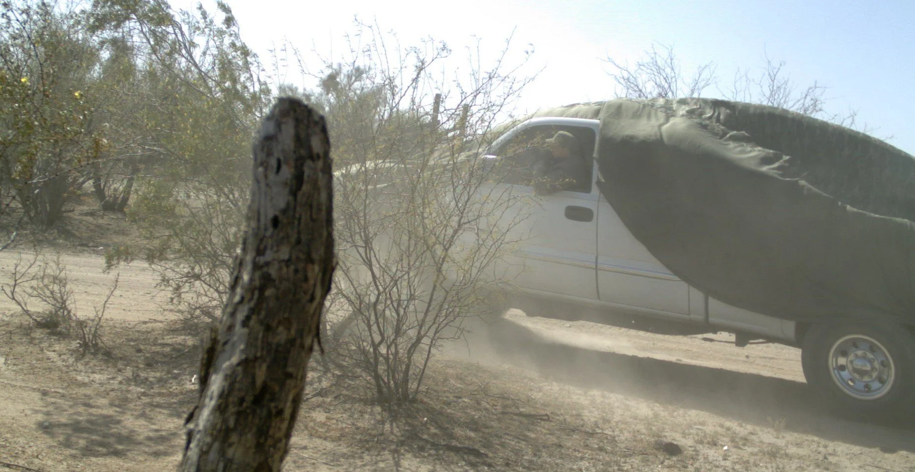 A load driver hangs out the window as the camouflage cover blows in the desert wind with his radio chirping with real-time directions from scouts positioned on mountaintops miles away. Scouts are guiding a multi-million dollar drug shipment around la