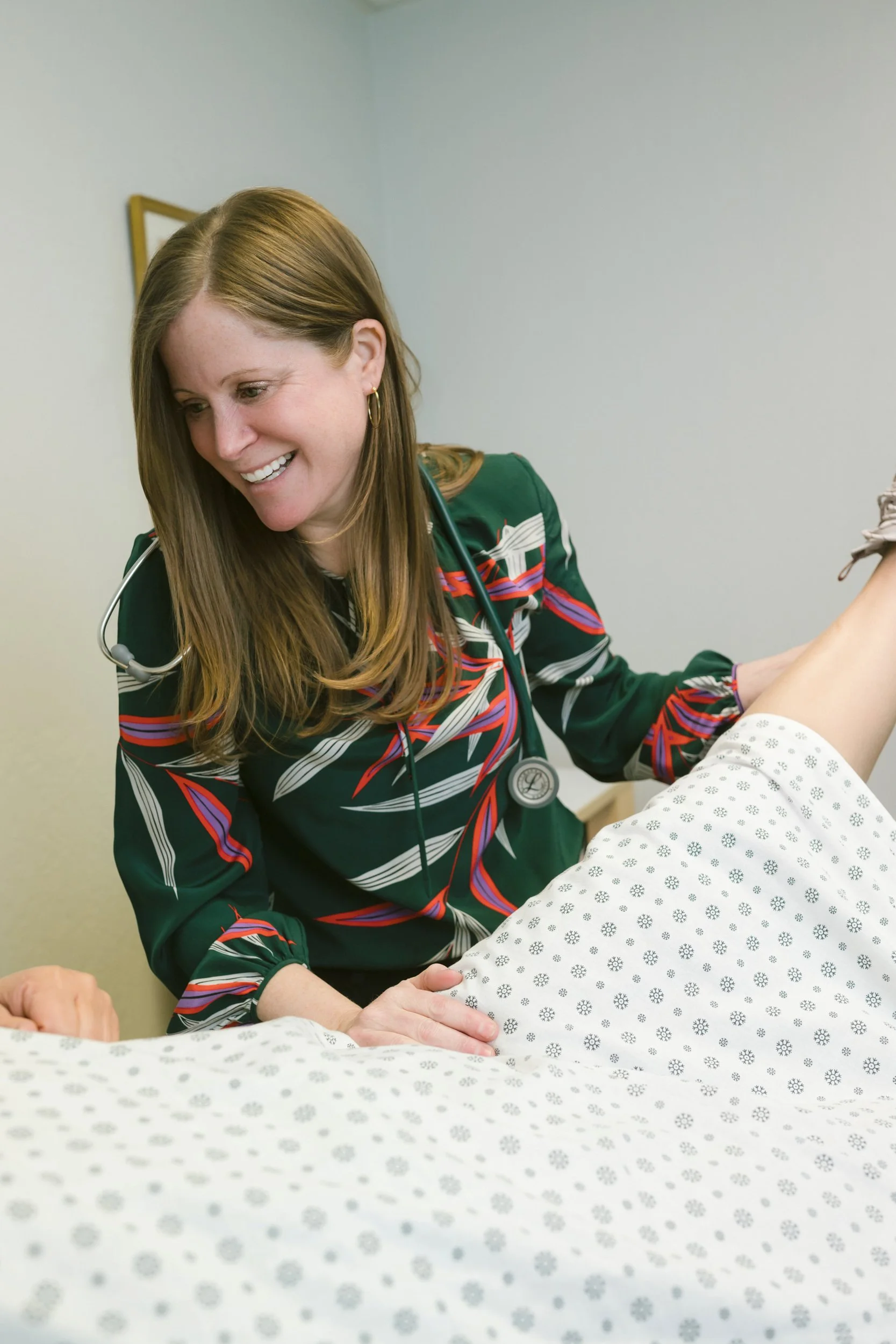 Clinician Dr. Christina Harding with a stethoscope smiling while examining a patient during an office visit