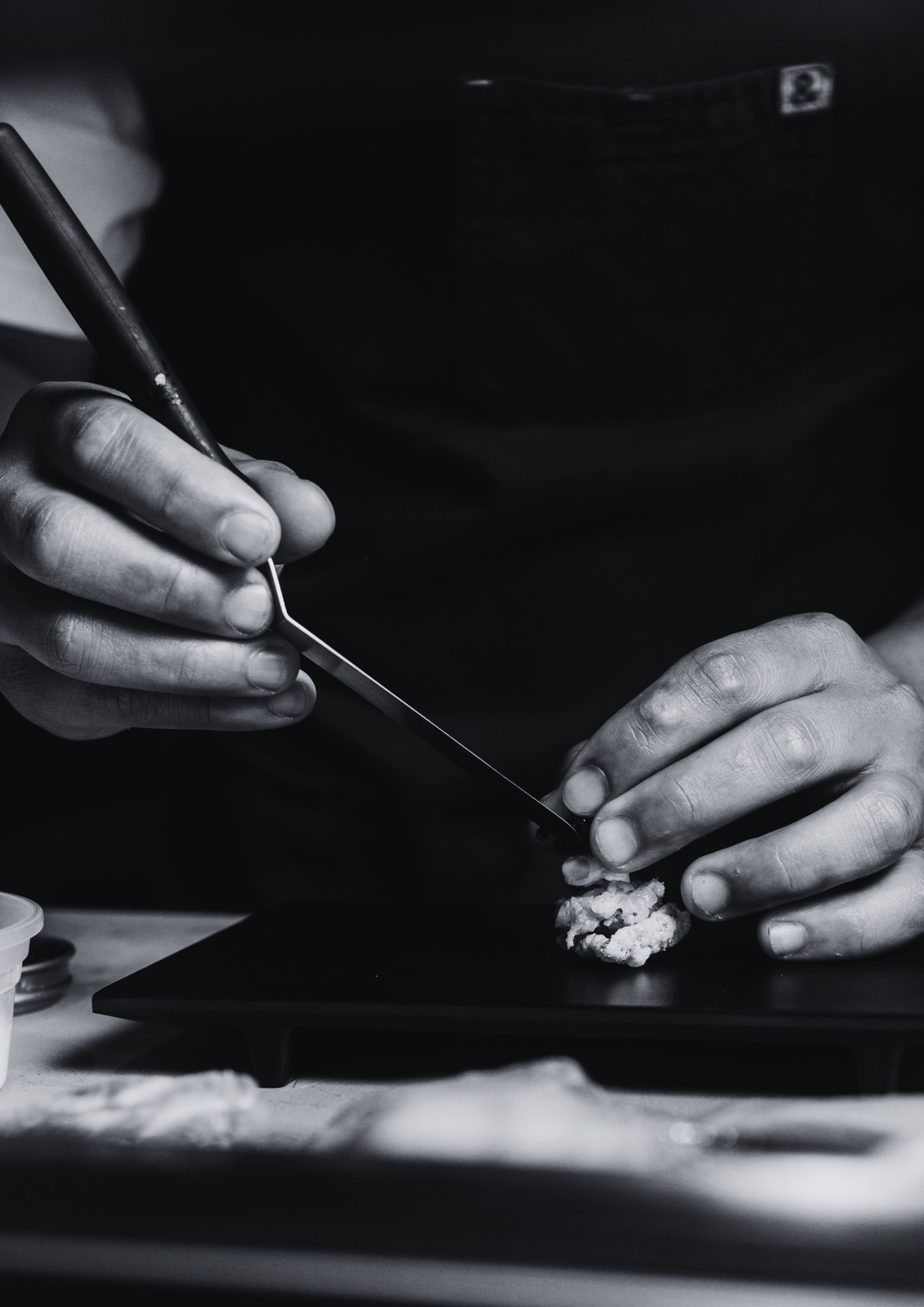 Close-up of a person using a precision tool to work on dinner, with focus on their hands.