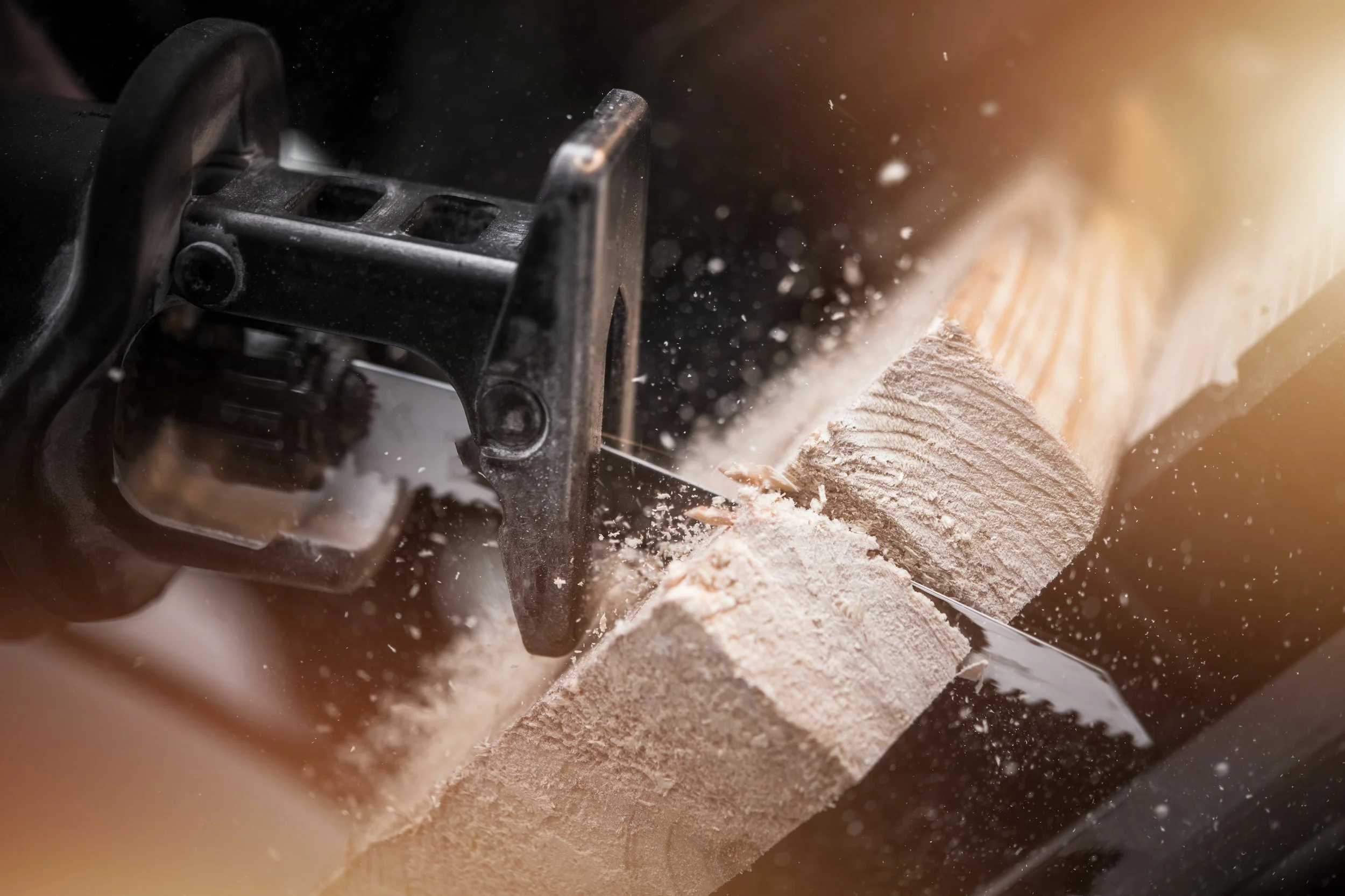 A close-up of a woodworker cutting a piece of wood with a circular saw, sawdust flying around.