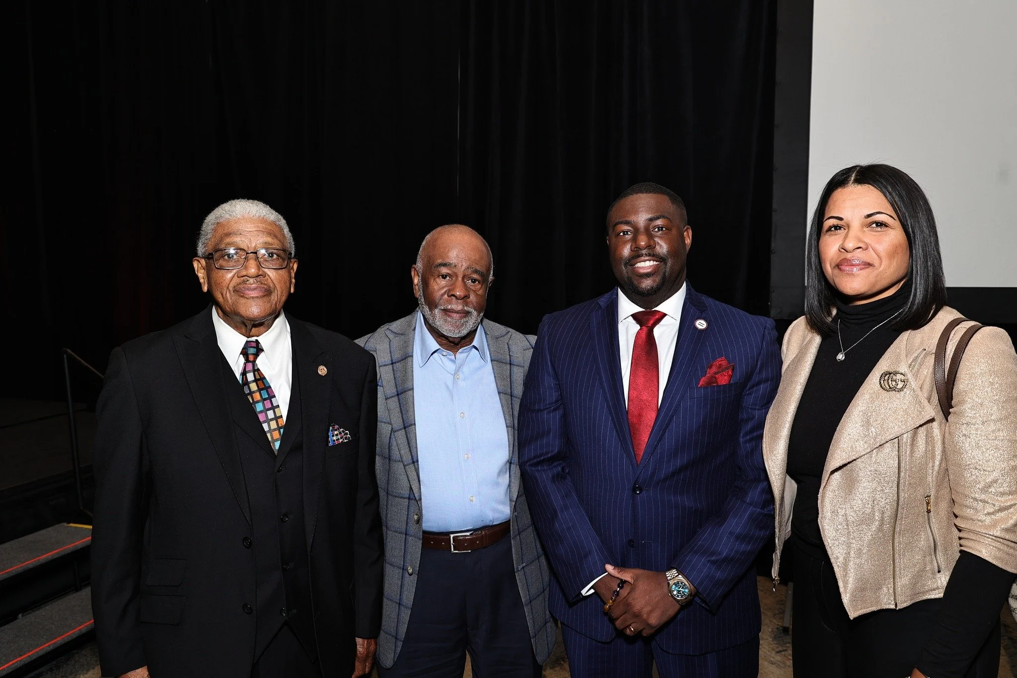 Group of four professionally dressed individuals standing together at an indoor event.