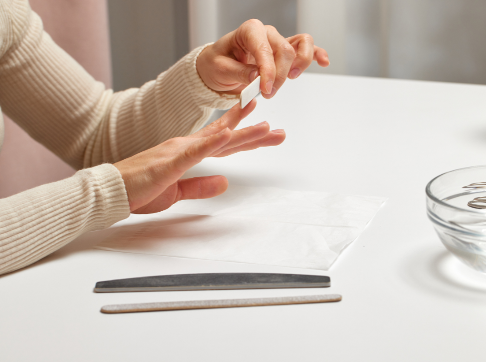 A woman is sitting at a table filing her nails.