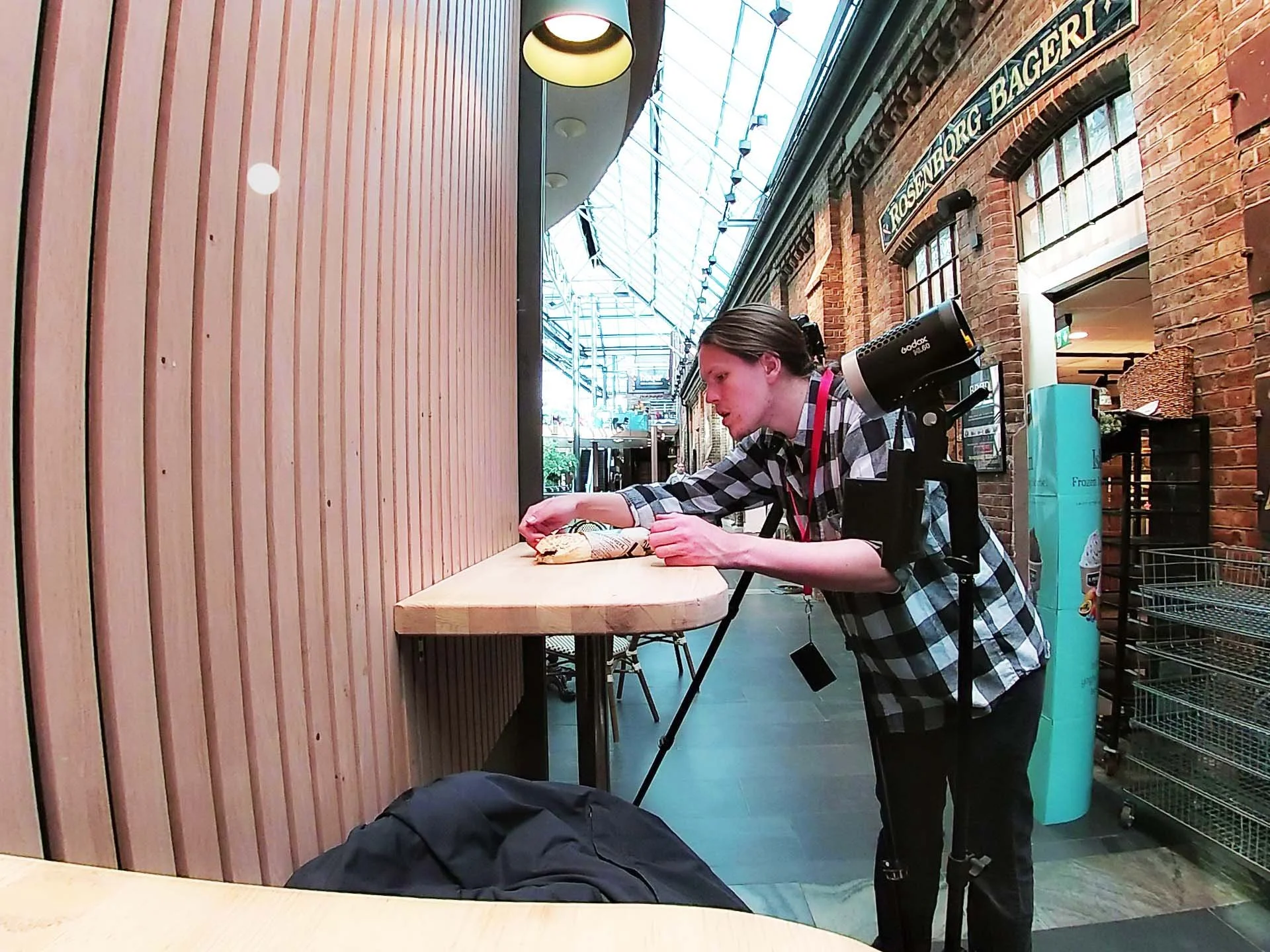 En person med fotografutstyr som tar bilder av en matvare på en hvilken som helst restaurant eller kafé.