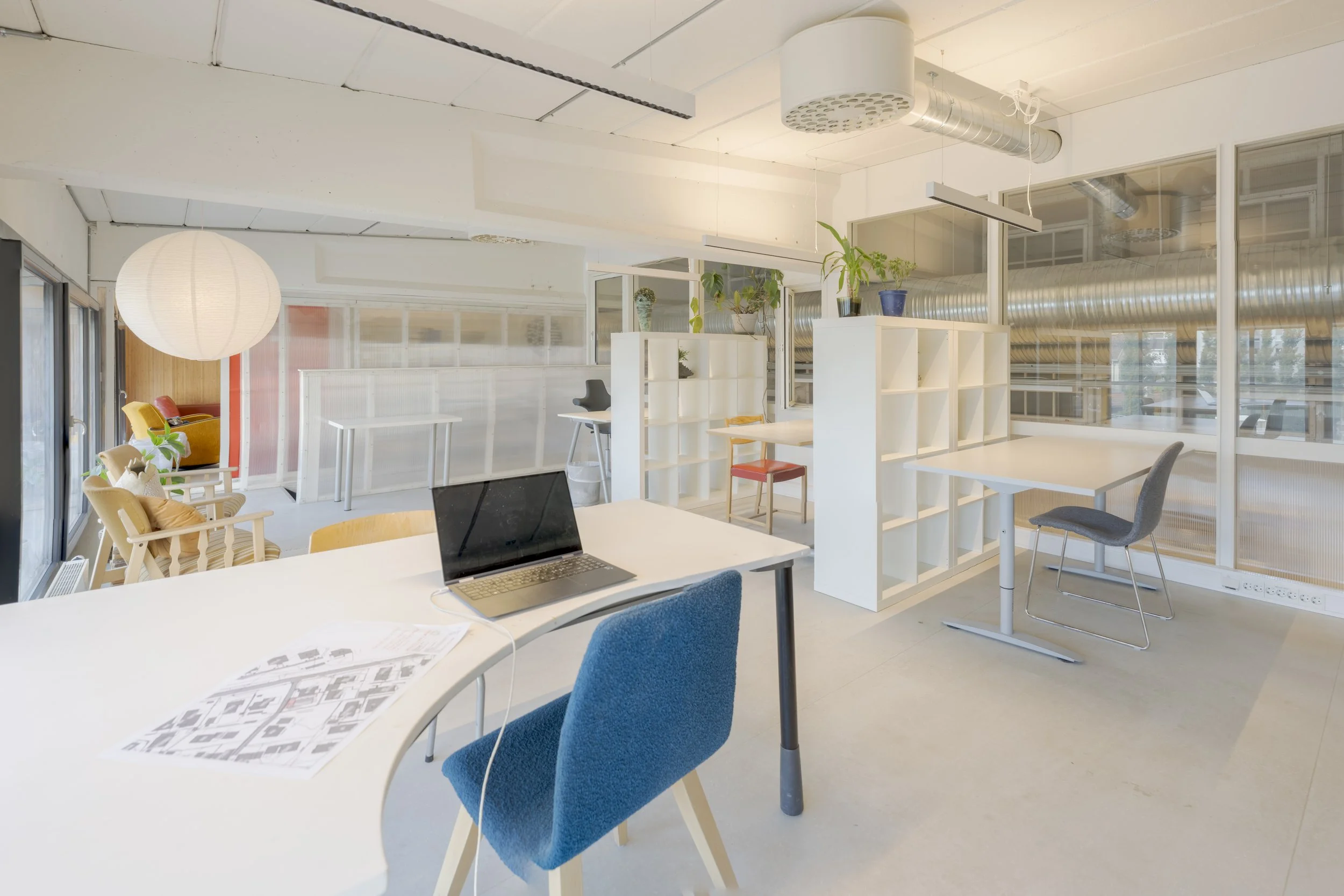 Et moderne kontorlandskap med store vinduer, hvite vegger og innendørs planter. Interiørbilder for Atelier Ilsvika. Foto: Scott Aune