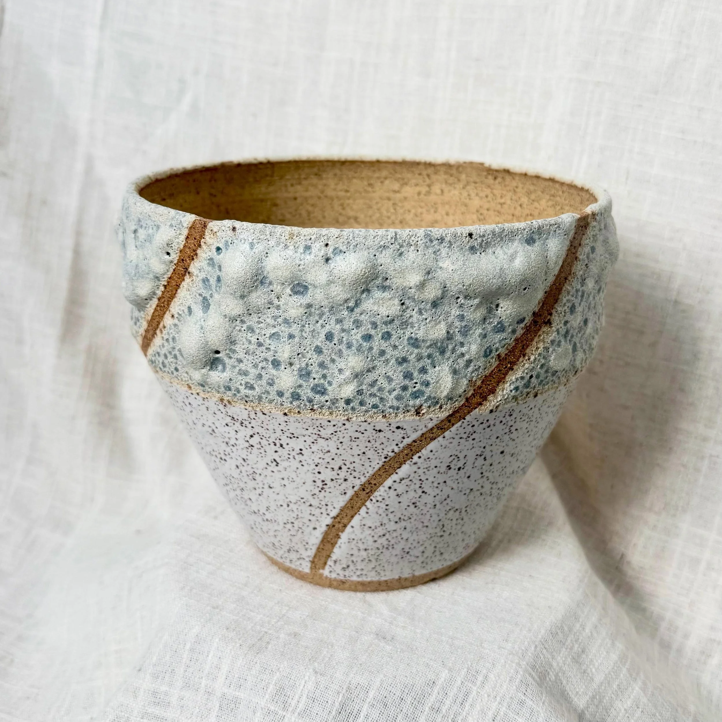 Speckled Lava Flower Pot 
Incorporated this hyper textured lava glaze and the clean crisp white, flowing all together with a bare stripe!
