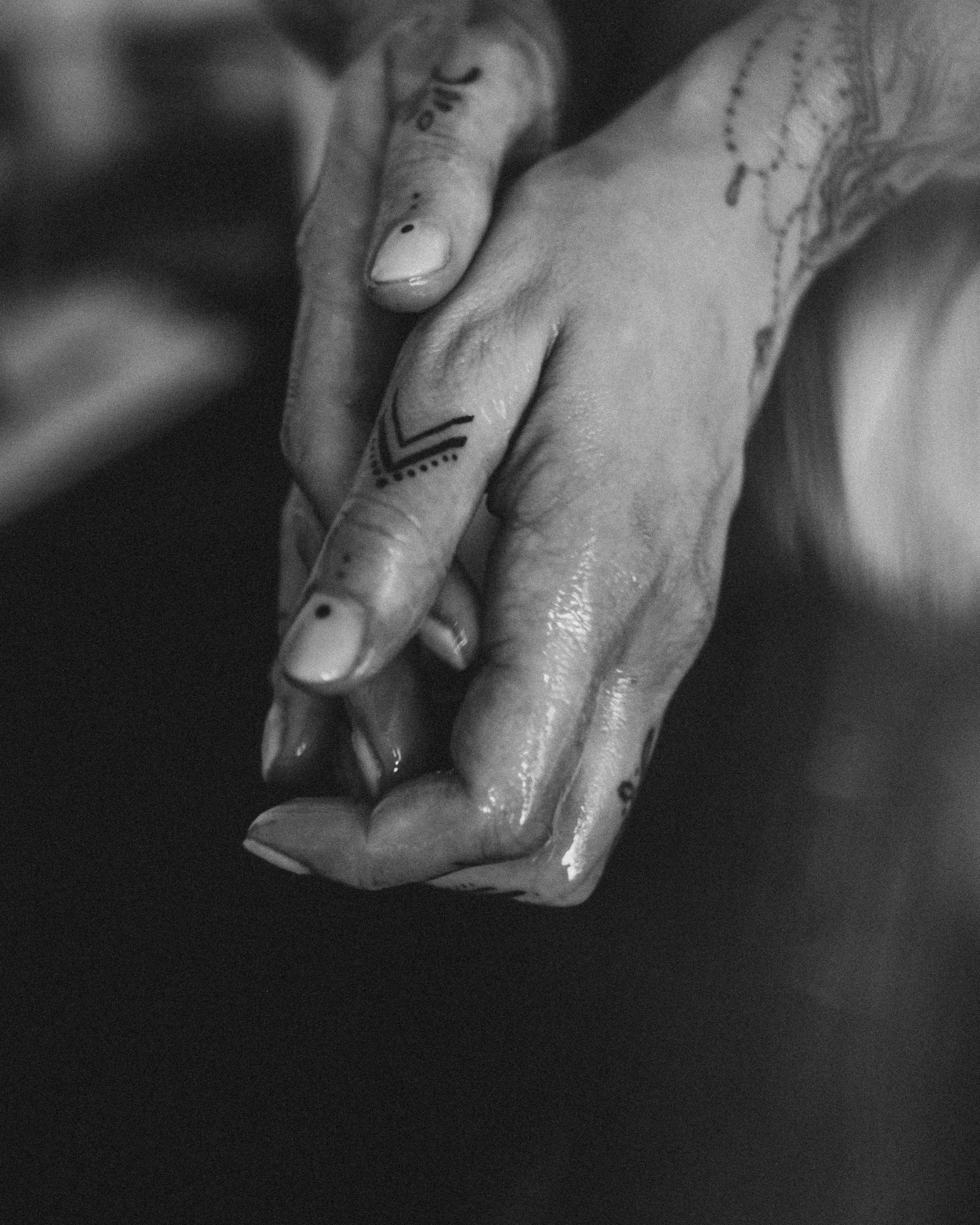 Nahaufnahme von zwei Händen mit Tätowierungen, die sich berühren.