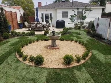 A circular gravel court with a classic fountain creates a focal point, framed by boxwood and a newly planted lawn