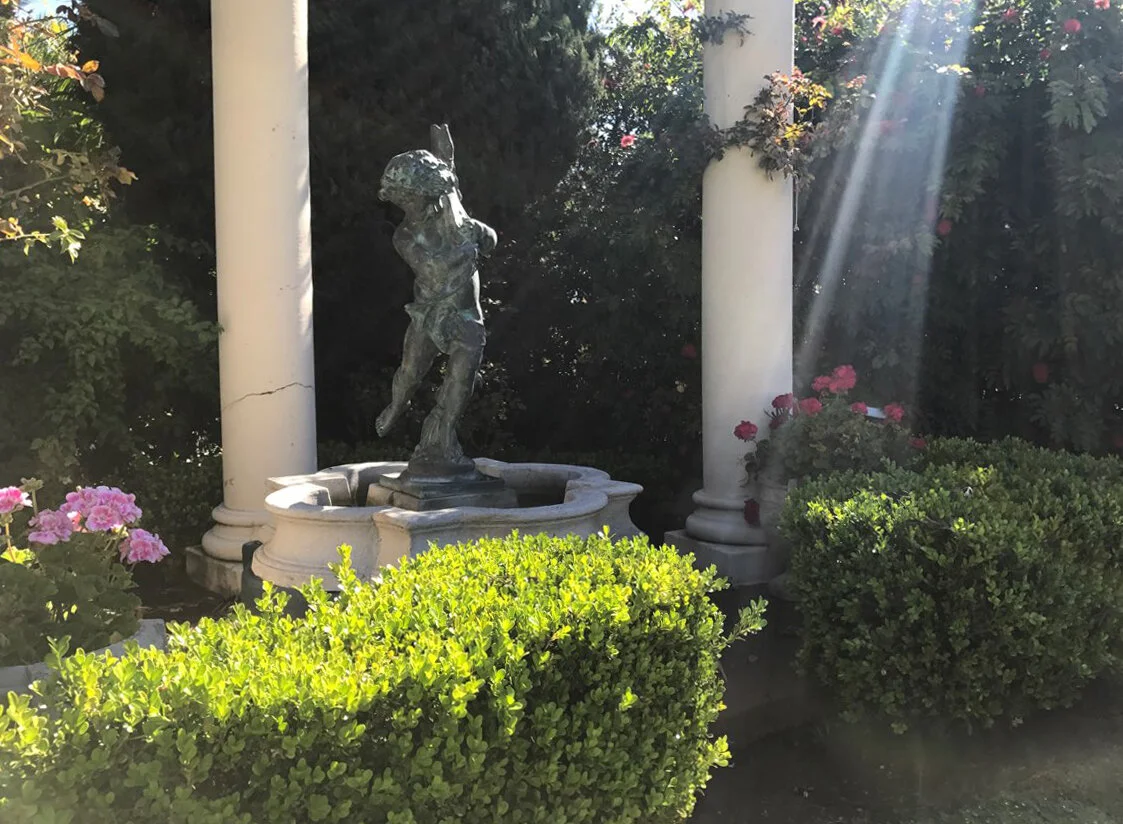 A charming fountain acts as a focal point inside a corner garden pergola