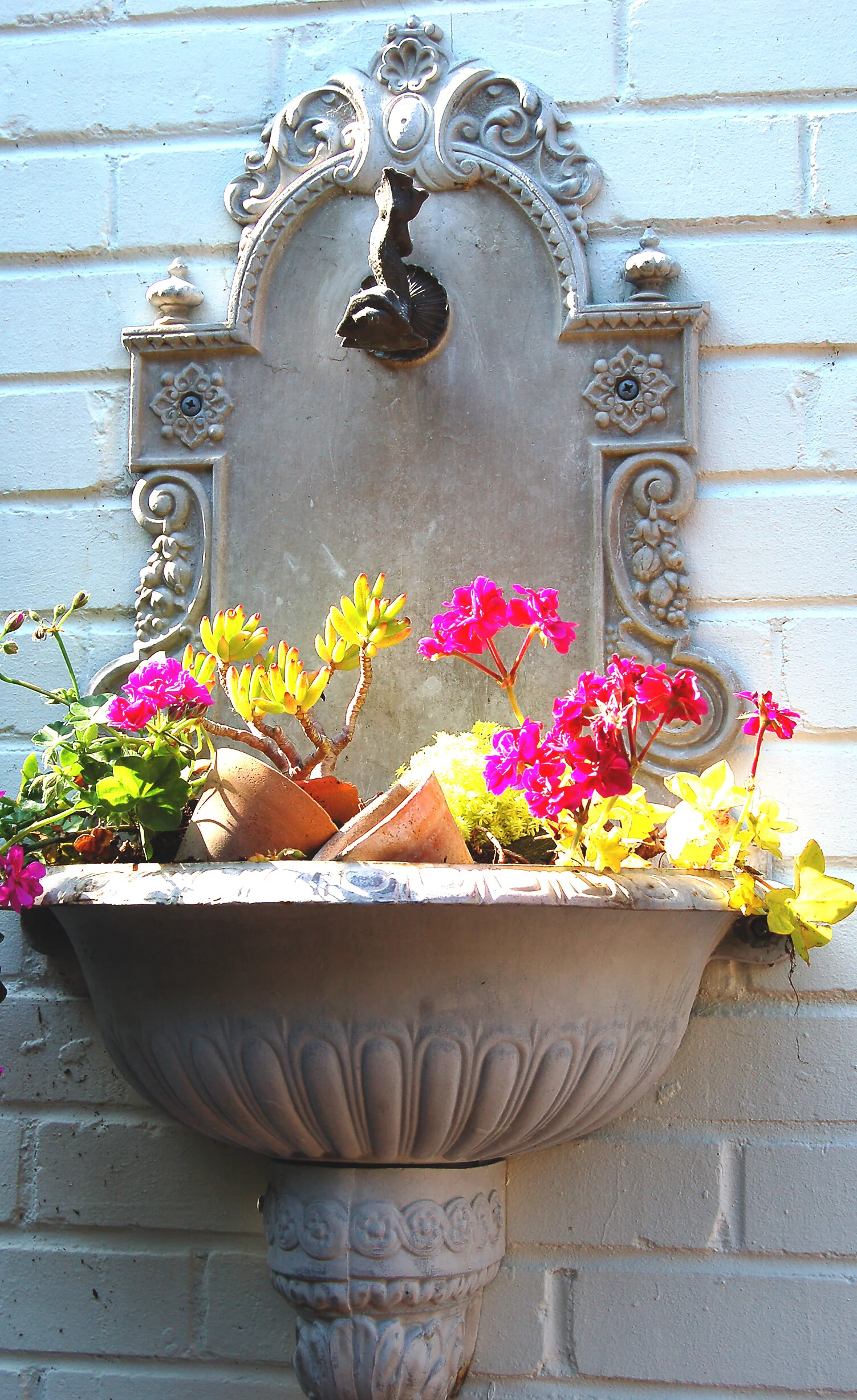 Antique wall fountain, planted basin, and terracotta pots—small details that make a garden special