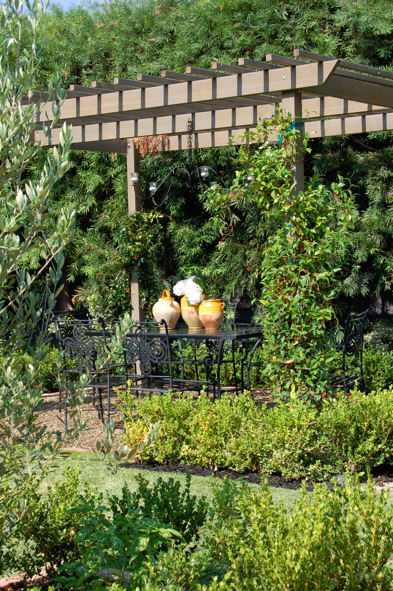 French antique confit pots are gathered on an iron garden table in this secluded Provence inspired garden