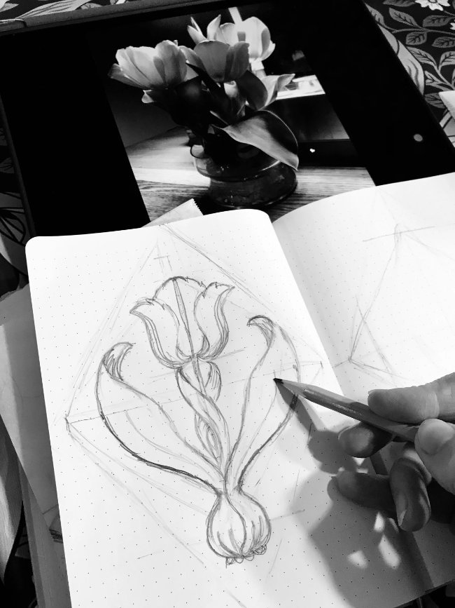 Refining a botanical floral motif in a sketchbook as part of the surface pattern design process.