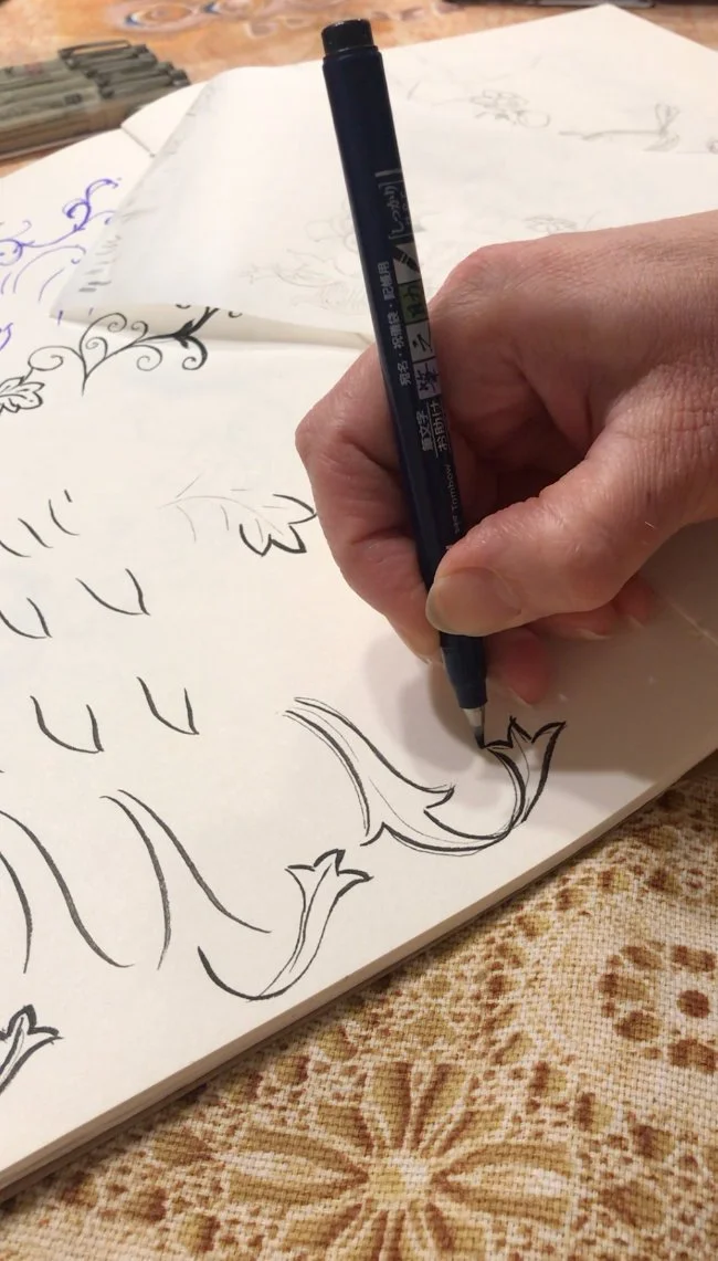 Hand drawing ornamental botanical motifs as part of the surface pattern design process.