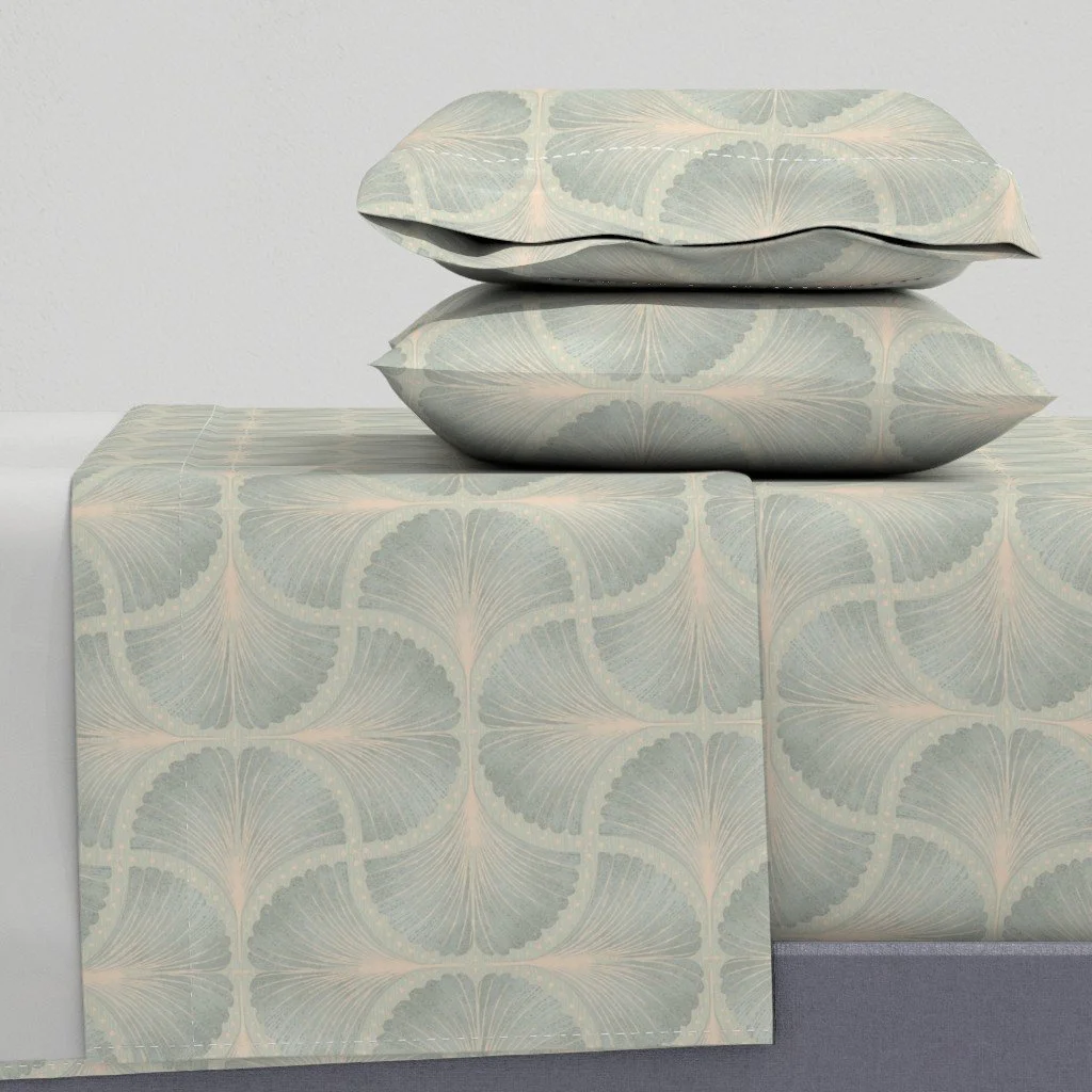 Two decorative pillows with a leaf pattern on a matching table covered with the same pattern fabric.