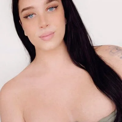 A young woman with long dark hair, blue eyes, and light skin looking at the camera with a neutral expression.