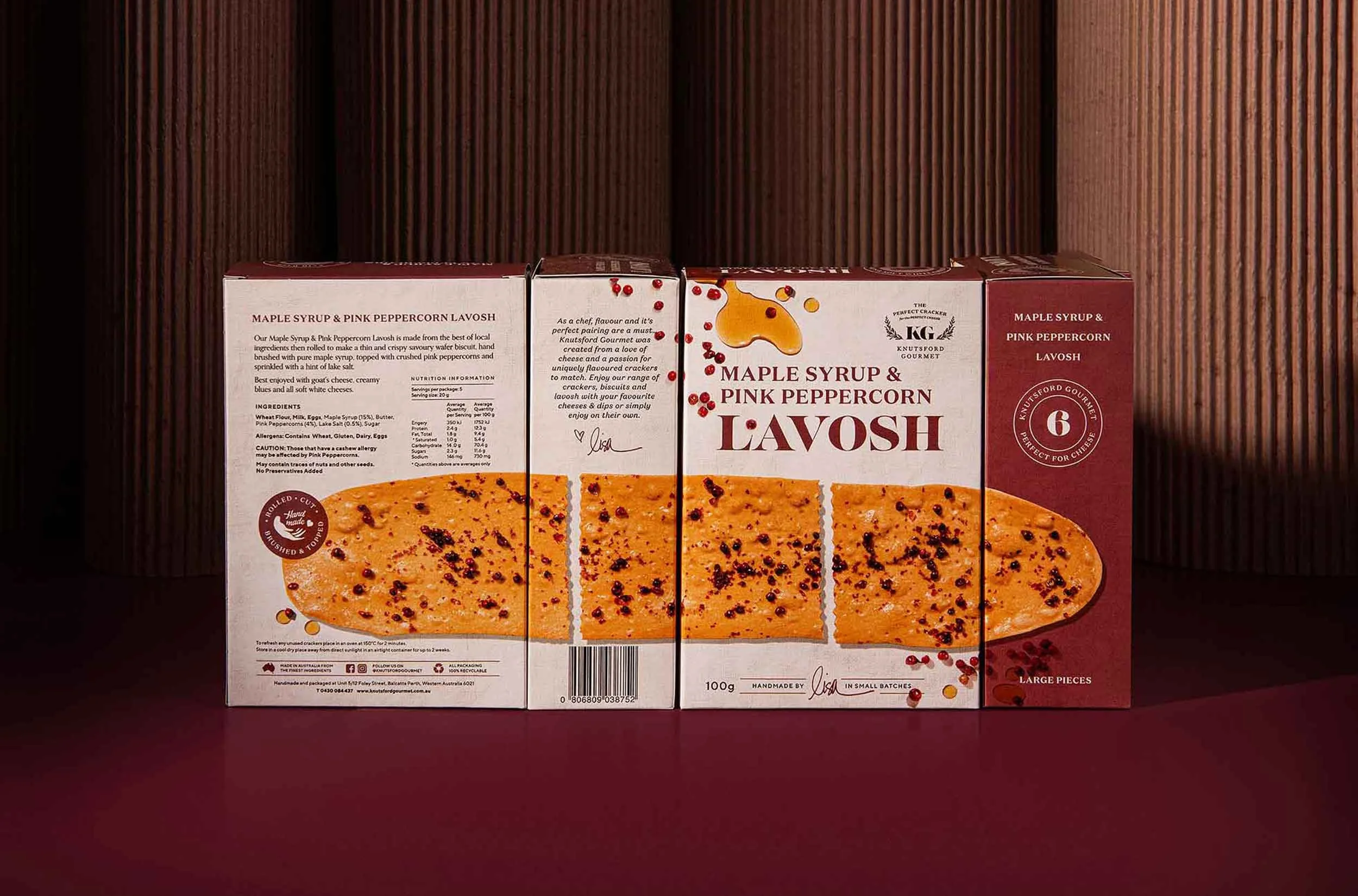 A stylised photograph of Knutsford Gourmet's Maple Syrup and Pink Peppercorn Lavosh packaging, showing the back, sides and front of the boxes