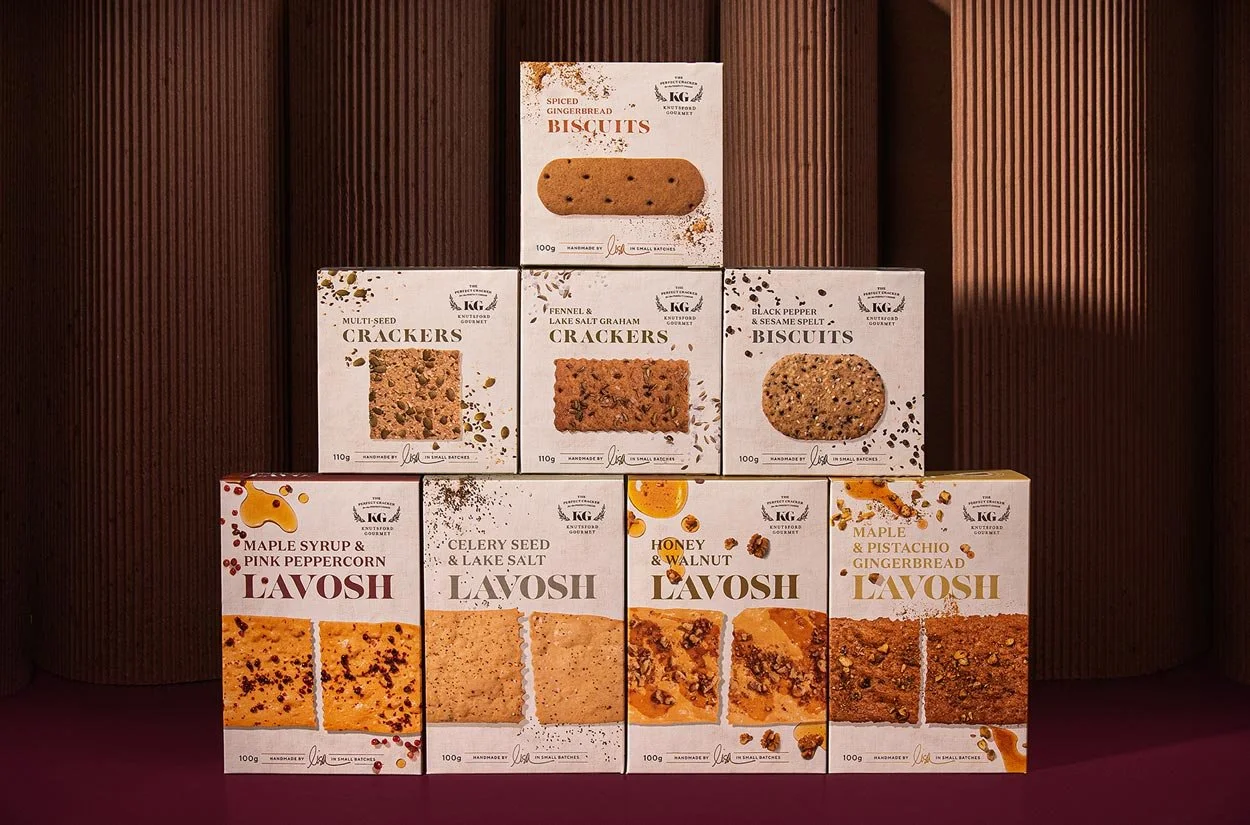 A stylised photograph of Knutsford Gourmet's biscuit, cracker and lavosh range, with all the packaging stacked in the shape of a pyramid
