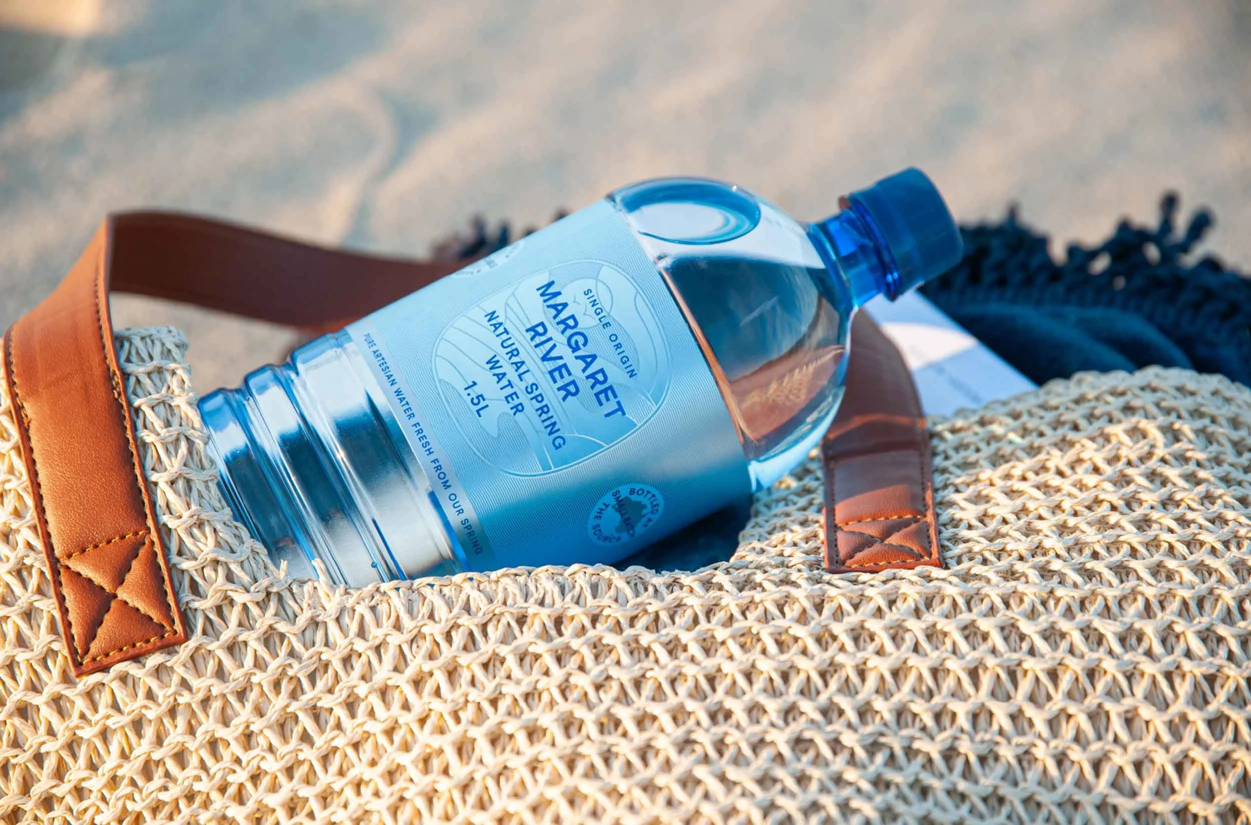 A 1.5 litre bottle of Margaret River Natural Spring Water sitting inside a woven beach bag