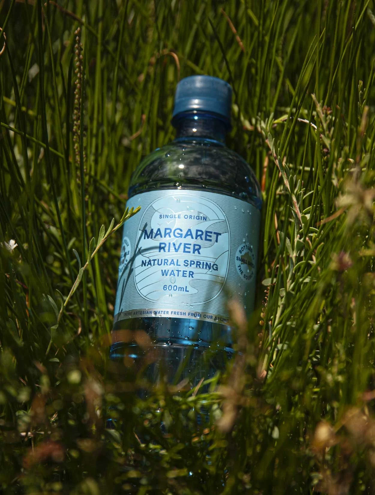 A 600ml Margaret River Natural Spring Water bottle lying in a field of tall grass