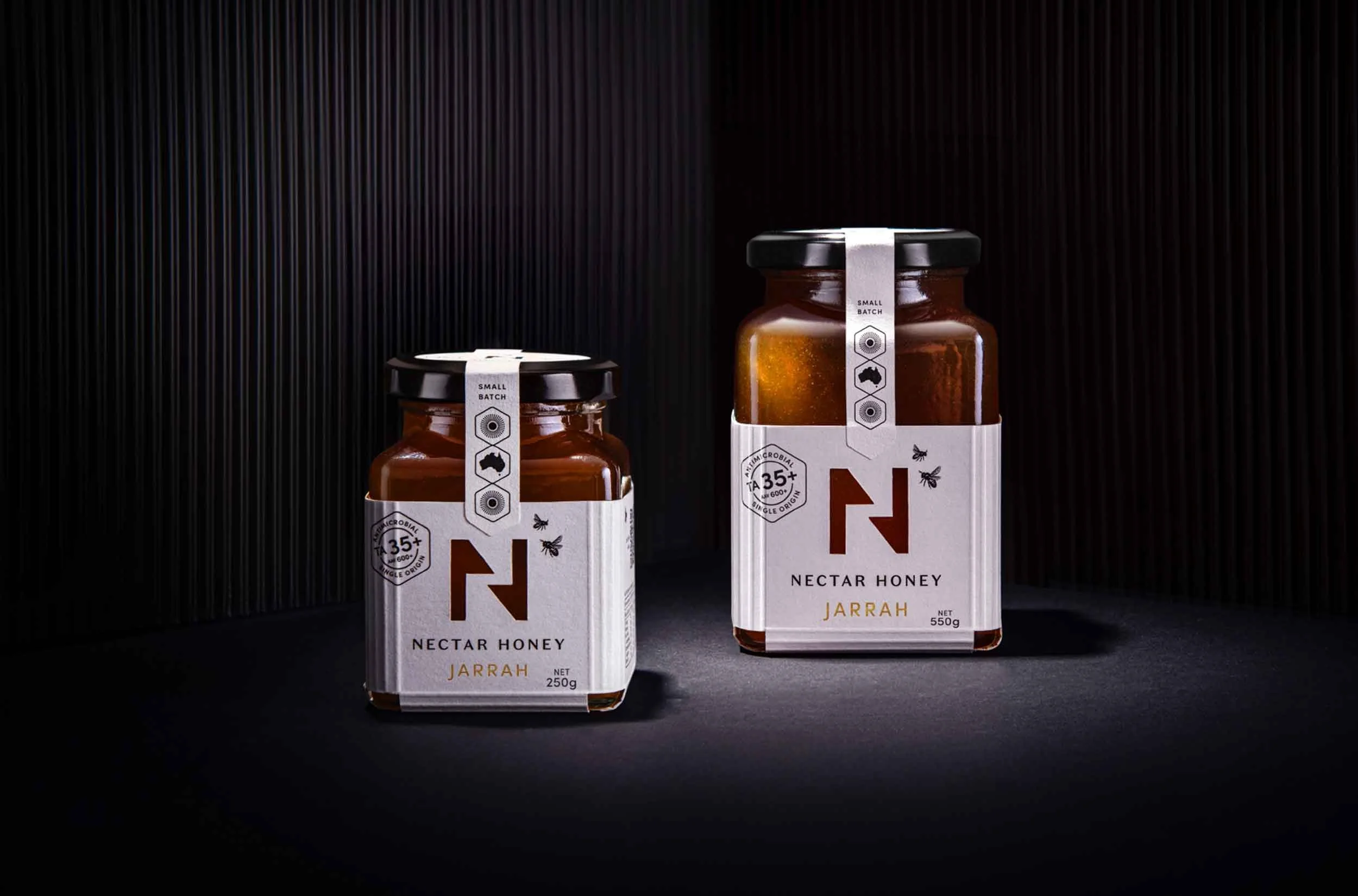 A stylised photograph of Nectar Honey's Jarrah honey with a 250g and 550g side by side jar