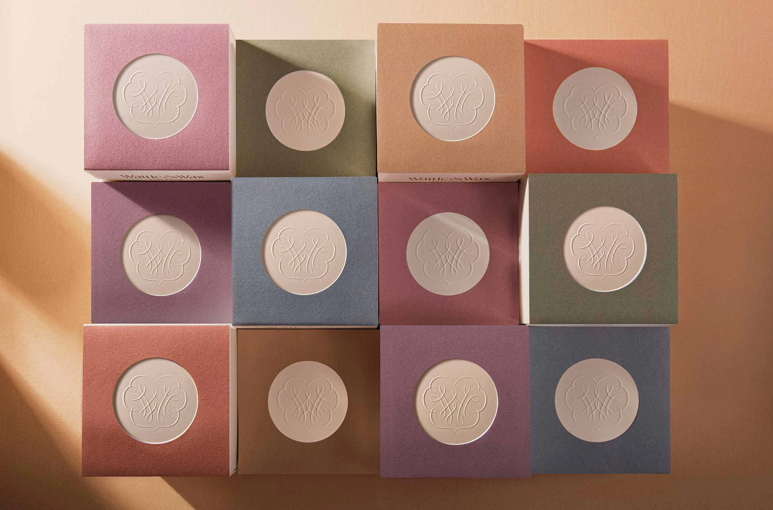A photograph of the top view of the Wattle and Wax candle boxes showcasing the embossed logo type