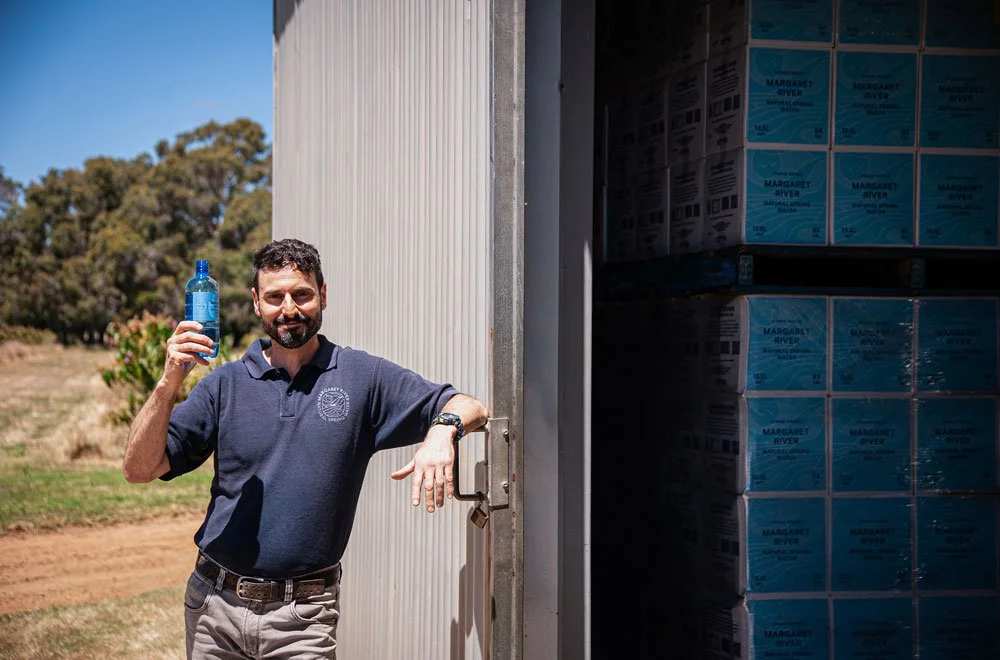 Serge, owner of Margaret River Natural Spring Water standing holding a bottle of Margaret River Natural Spring Water