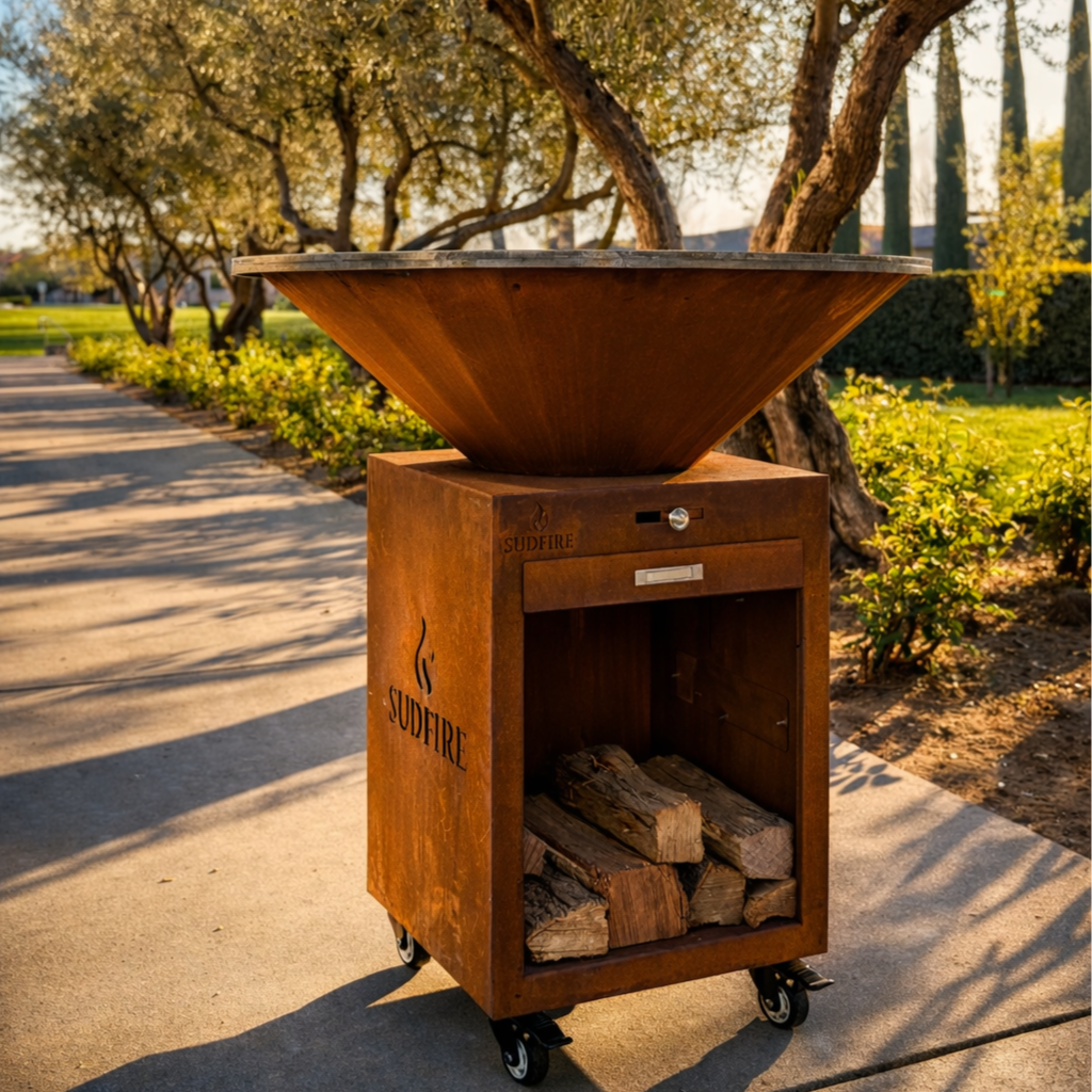 Sudfire Hearth 39 outdoor fire pit grill with wood storage, modern backyard live fire cooking setup at sunset