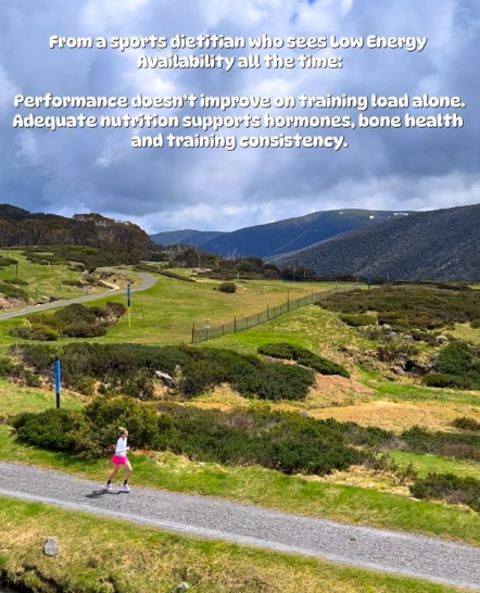 A person jogging on a gravel path through a lush green landscape with rolling hills and mountains in the background. Overlaid text discusses sports diet, low energy availability, performance, nutrition, hormones, bone health, and training consistency.