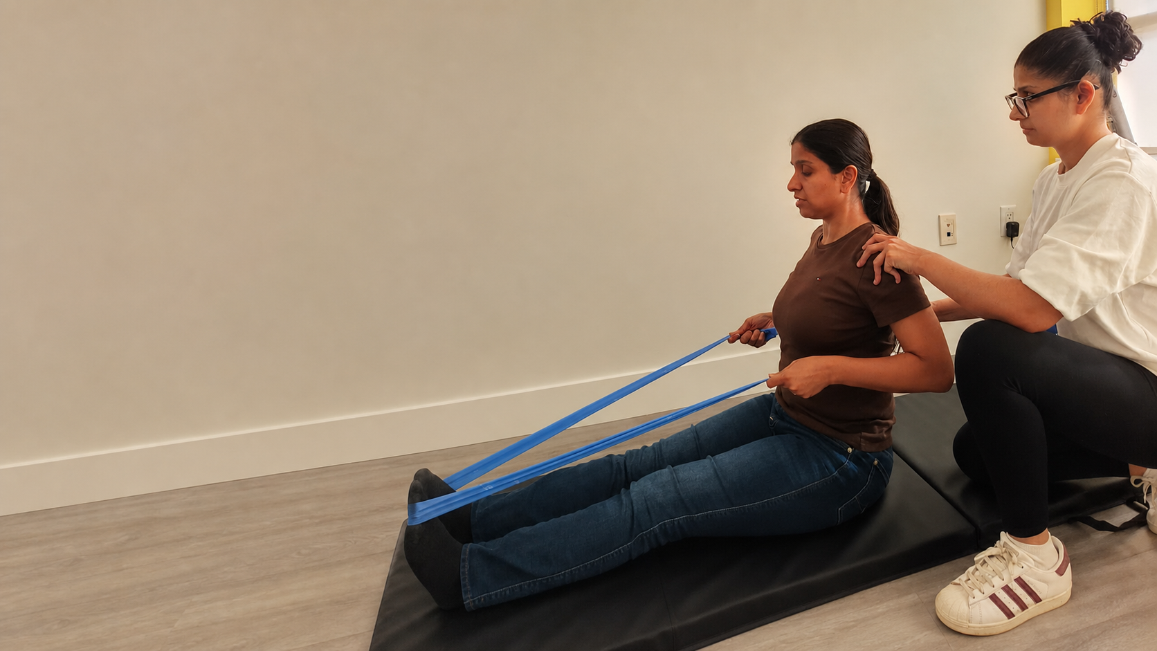 Physiotherapist guiding a patient through a seated shoulder resistance exercise at WellCare Physiotherapy in Surrey