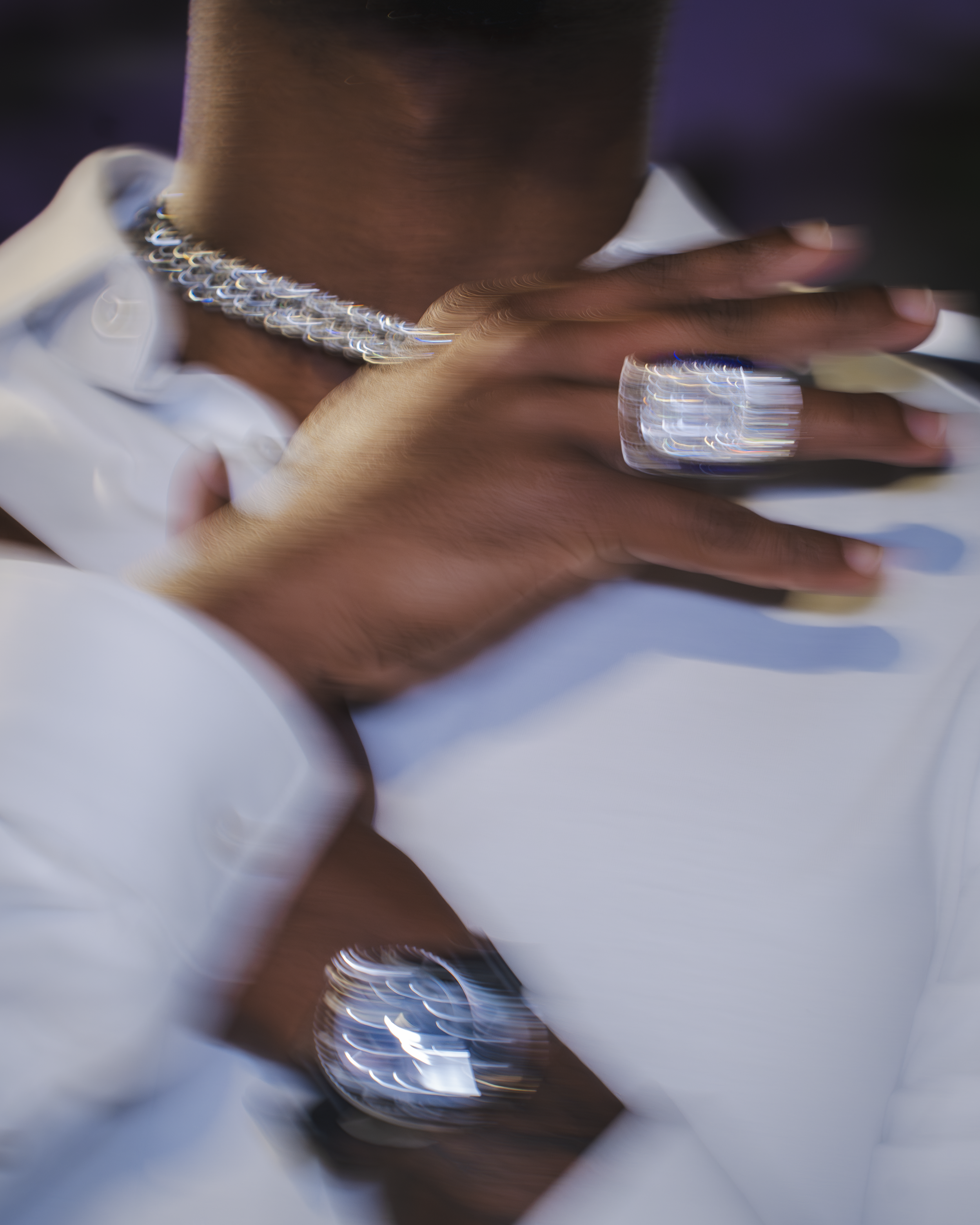 Close-up of a person wearing jewelry, with a blurry reflection and lighting effects creating a distorted, artistic image.