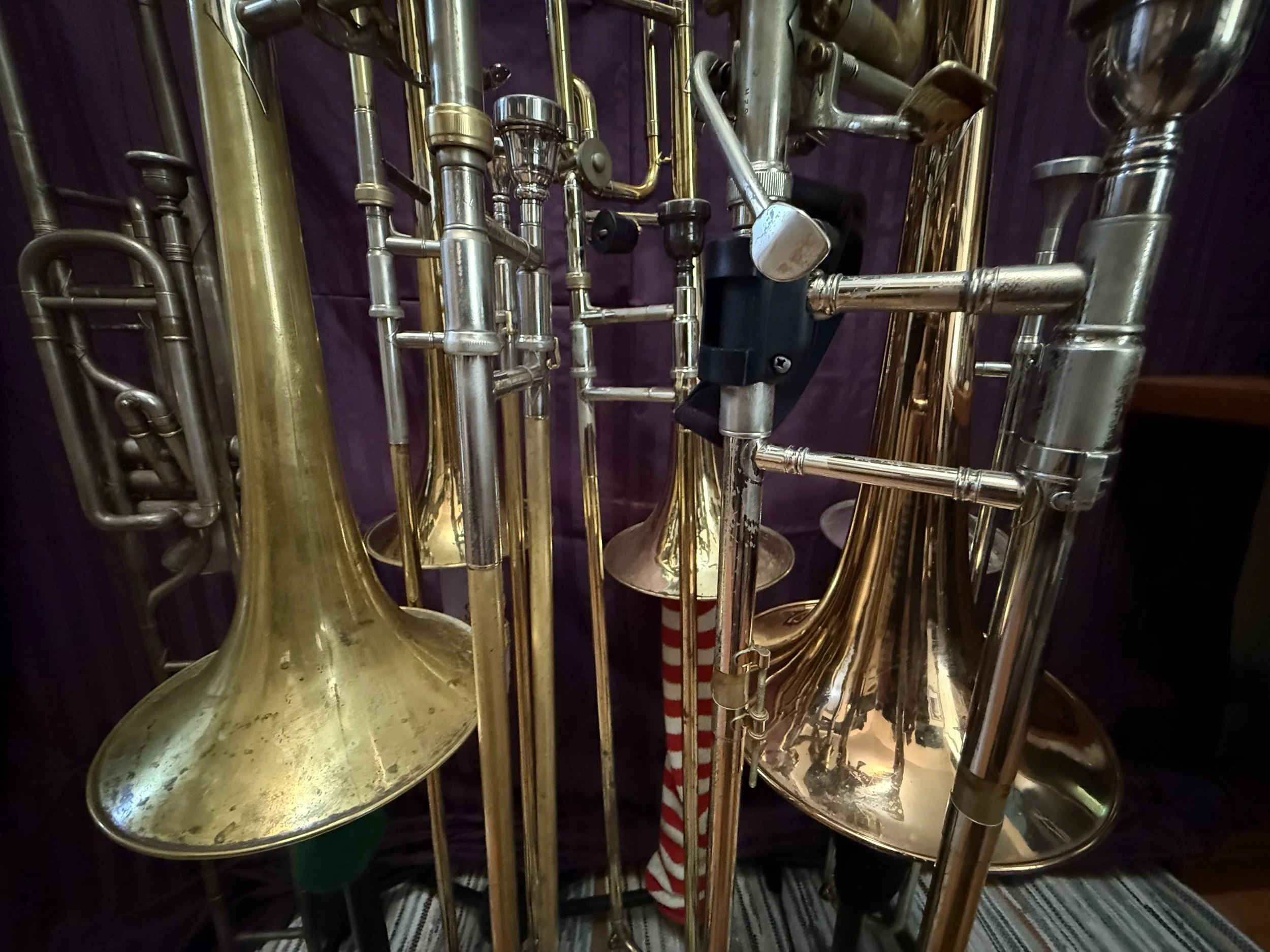 Close-up of brass and silver musical instruments, including trumpets and tubas, displayed together.