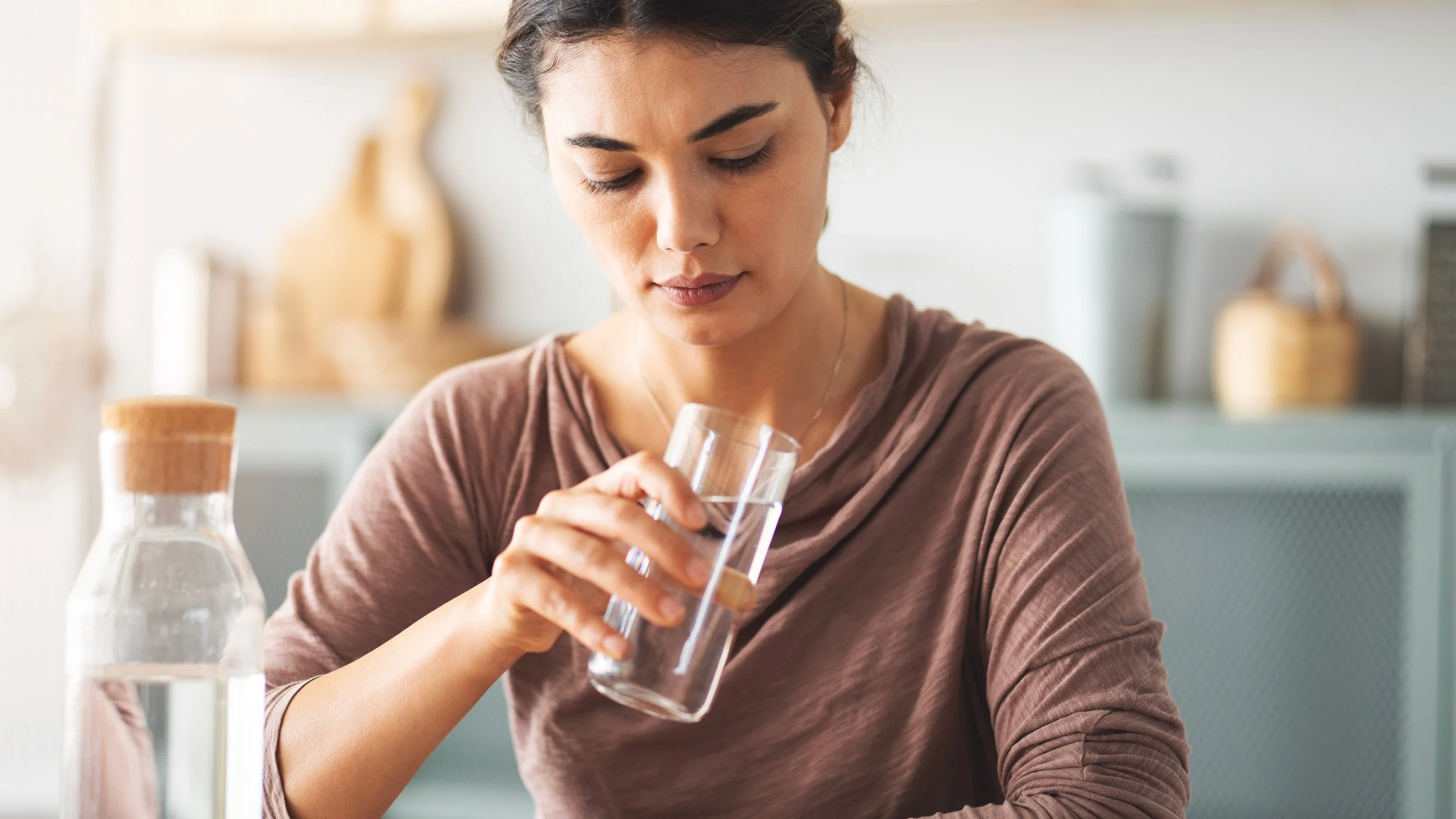 Woman enjoying a glass of clean, filtered drinking water with a ClearHaven whole-home water filtration system in a Perth home.