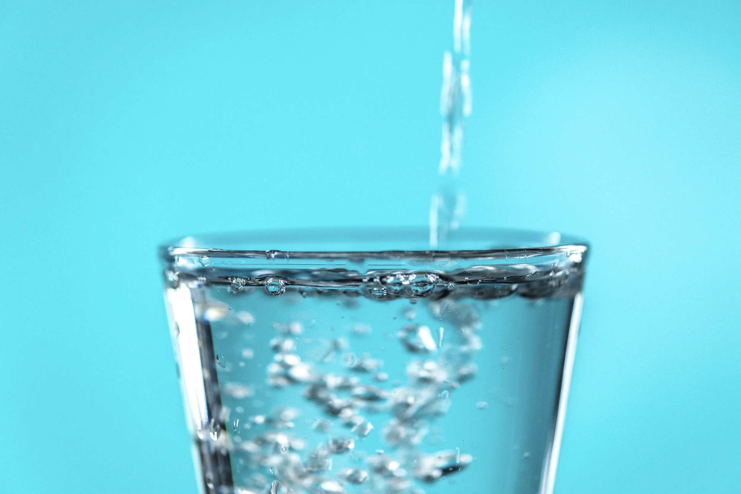 Glass of clean drinking water being filled, illustrating filtered water for Perth homes and the benefits of reducing PFAS and other contaminants with whole-home water filtration.