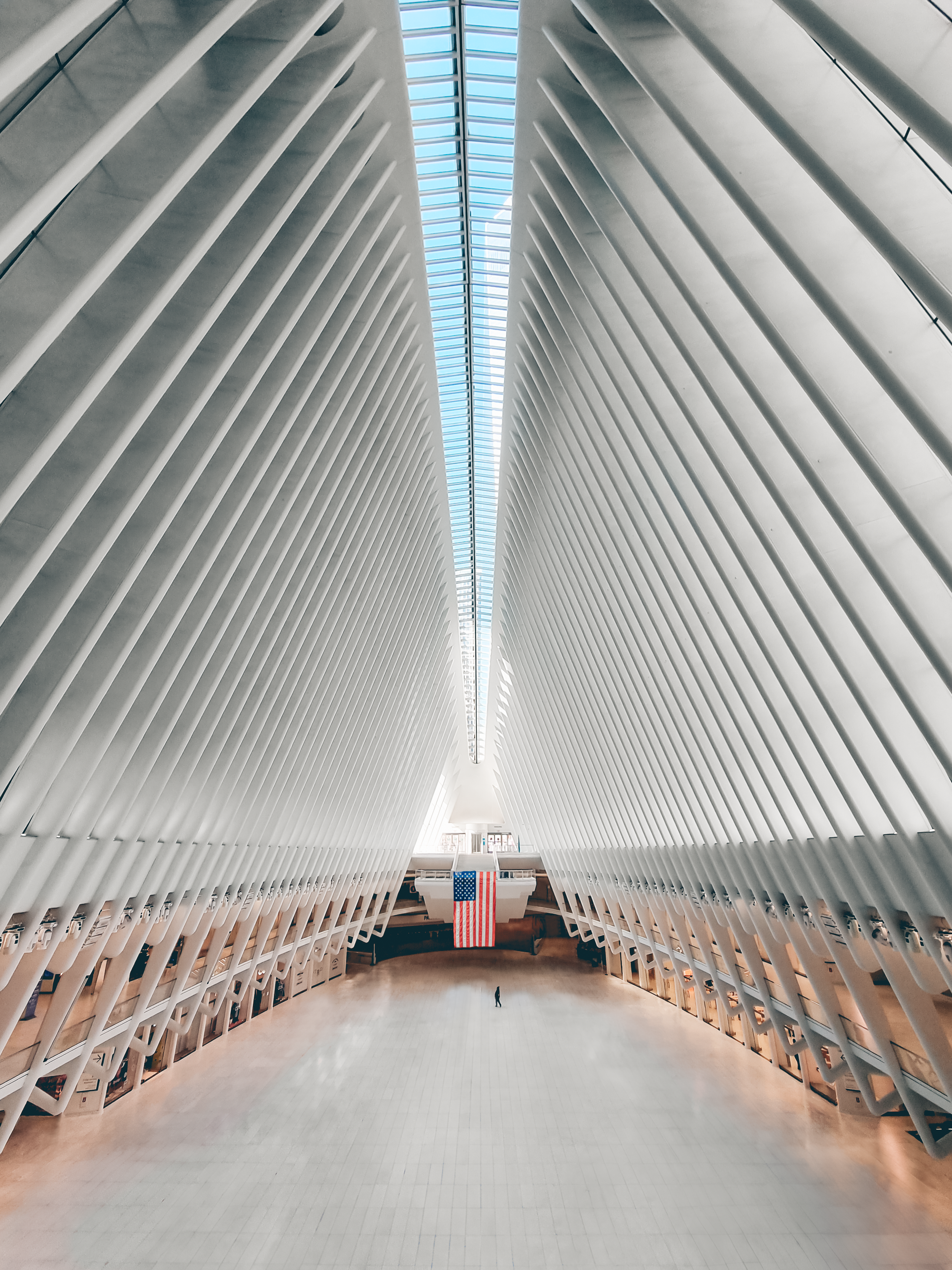 Interior of the Oculus transportation hub with white architectural supports and an American flag hanging in the center.