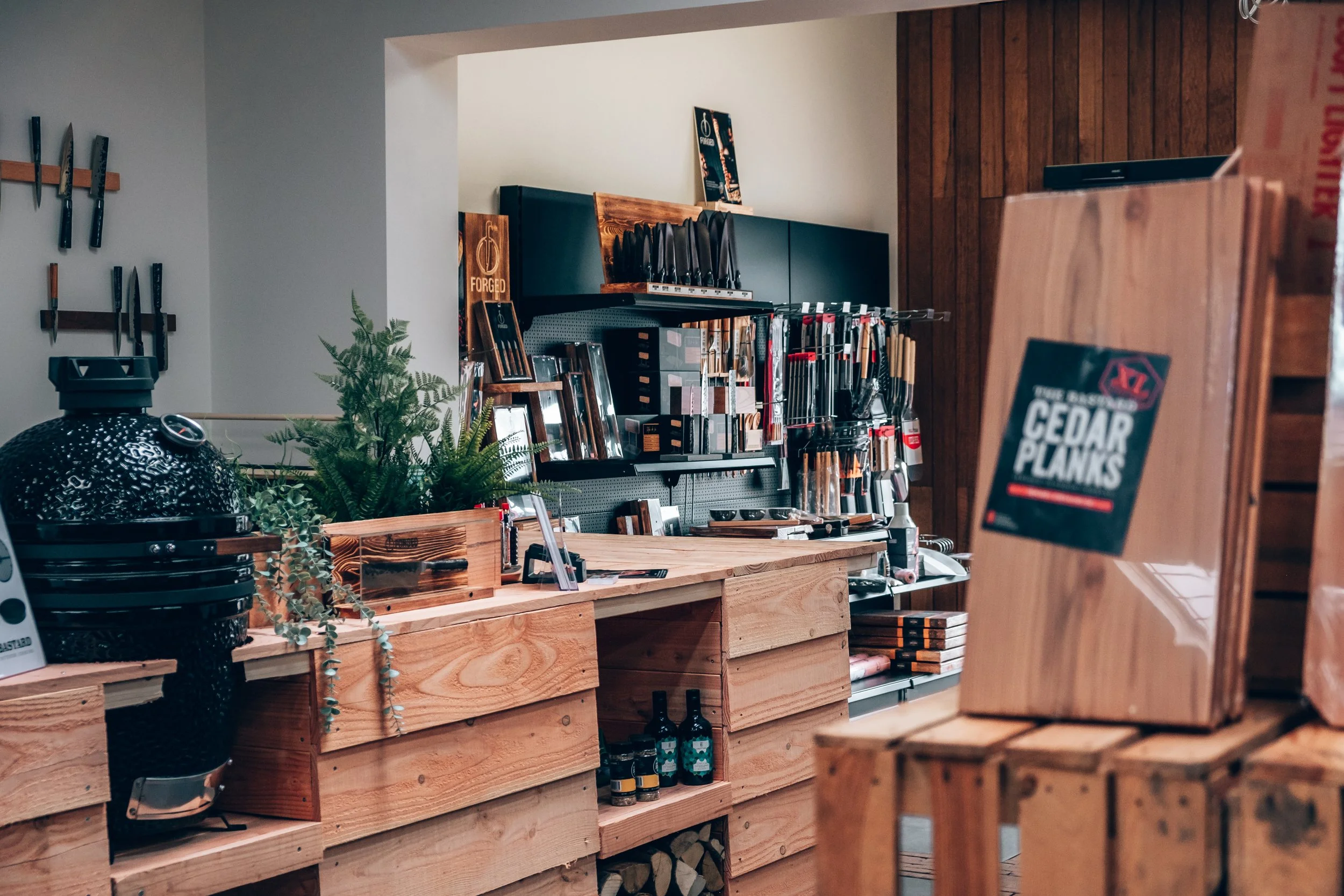 Display of woodworking tools and supplies in a store with wooden shelves and a pegboard holding knives and other tools.