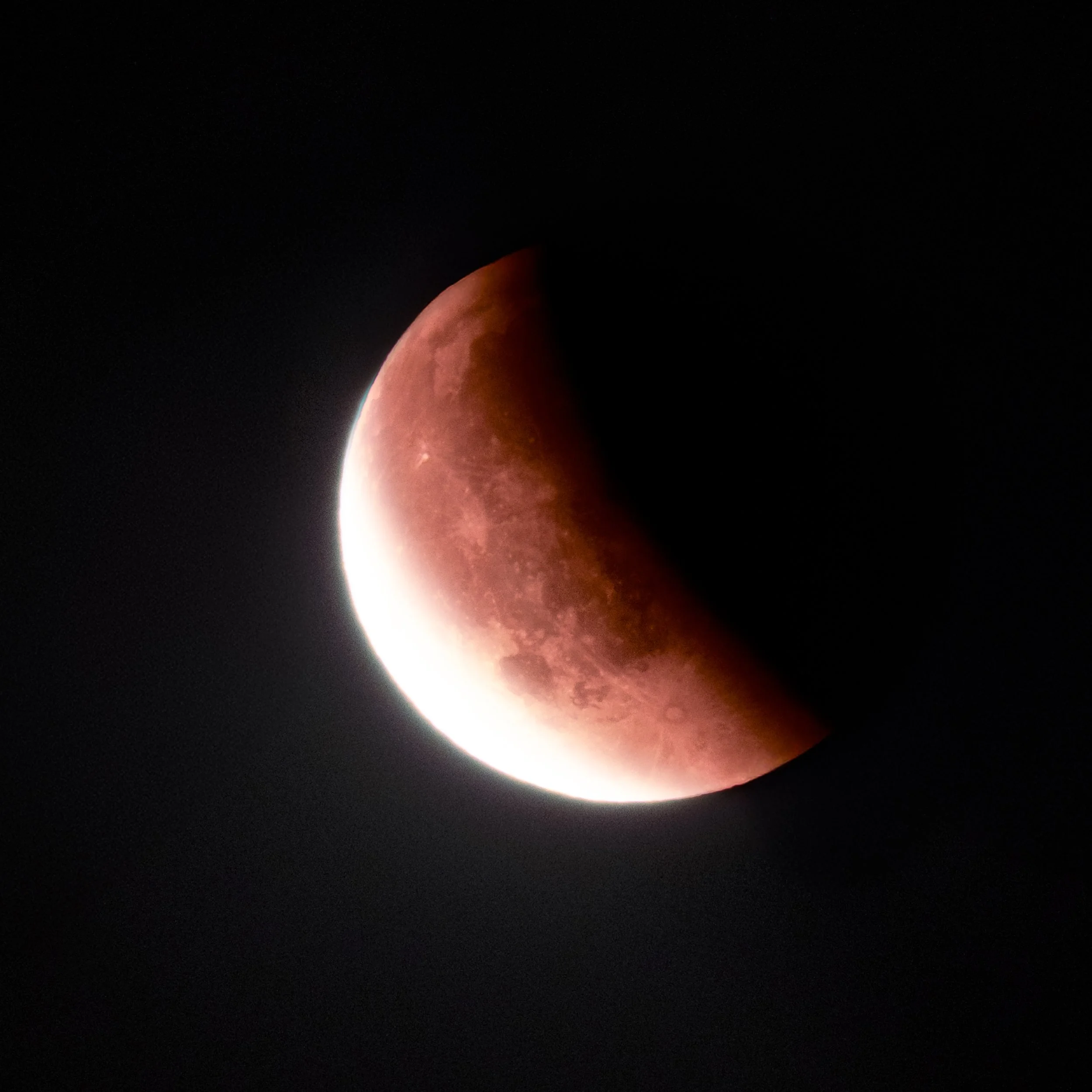 A photograph of a lunar eclipse showing the moon in a reddish hue against a black night sky.