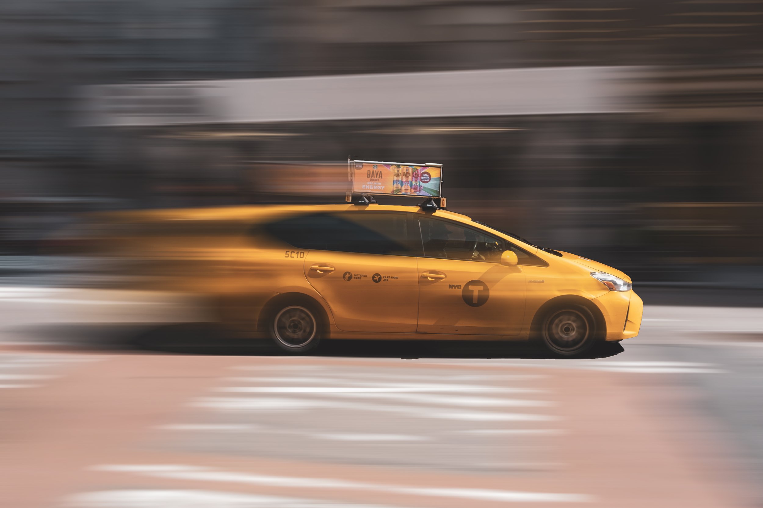 A yellow NYC yellow taxi cab moving quickly through the city streets, captured in motion blur. NEW YORK CITY CAB