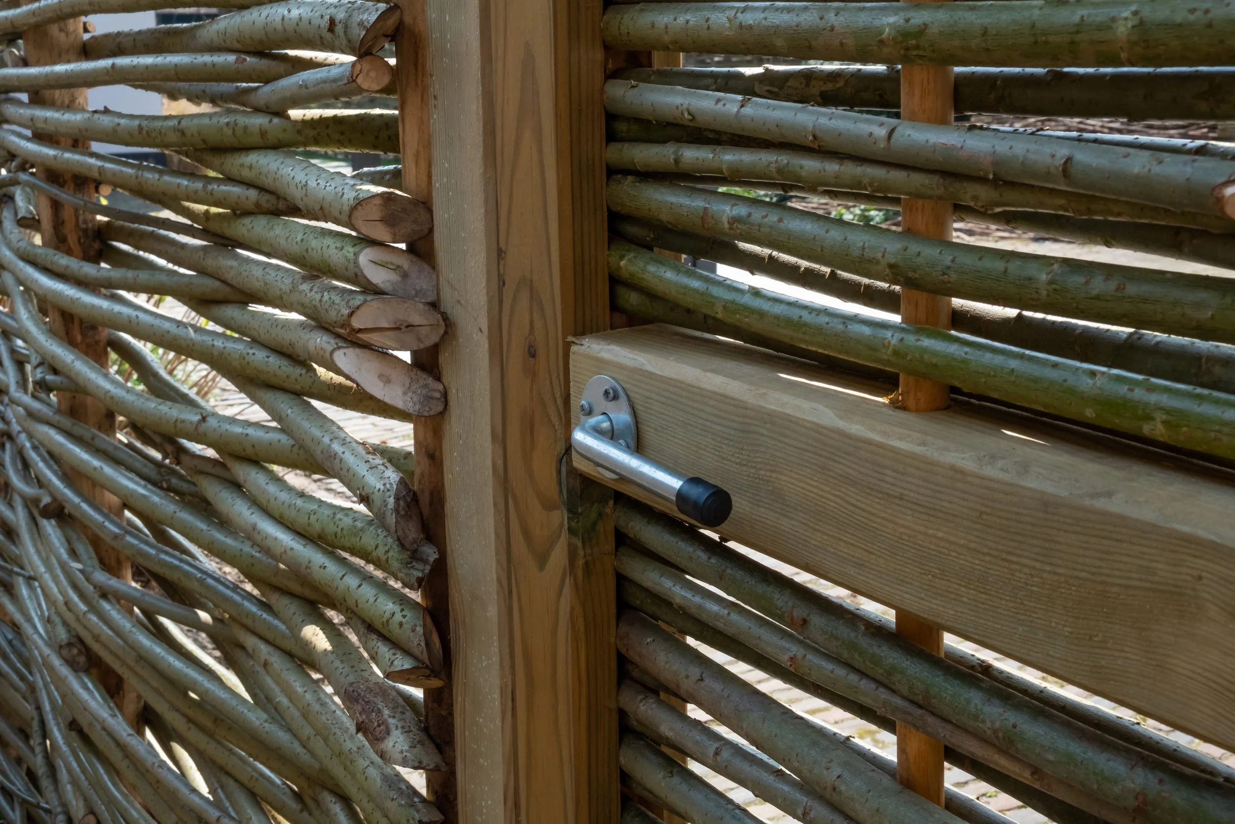 Close-up of a wooden and bamboo gate with a metal latch.