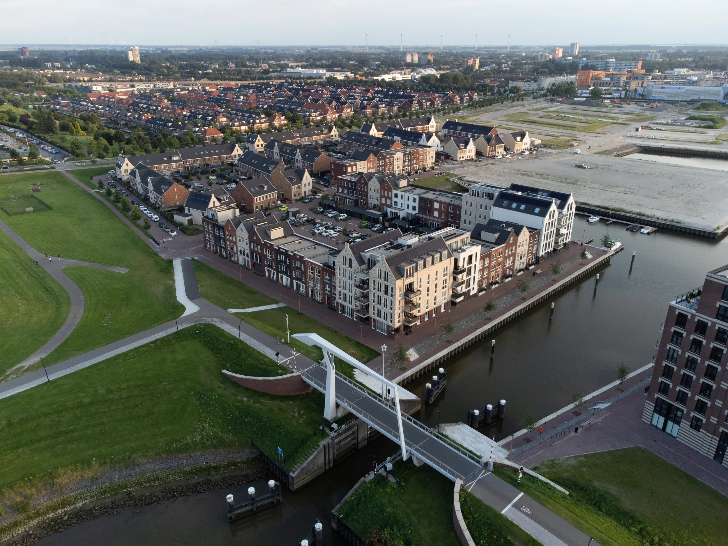 Aerial view of a modern residential area with green parks, water channels, and apartment buildings in the background.