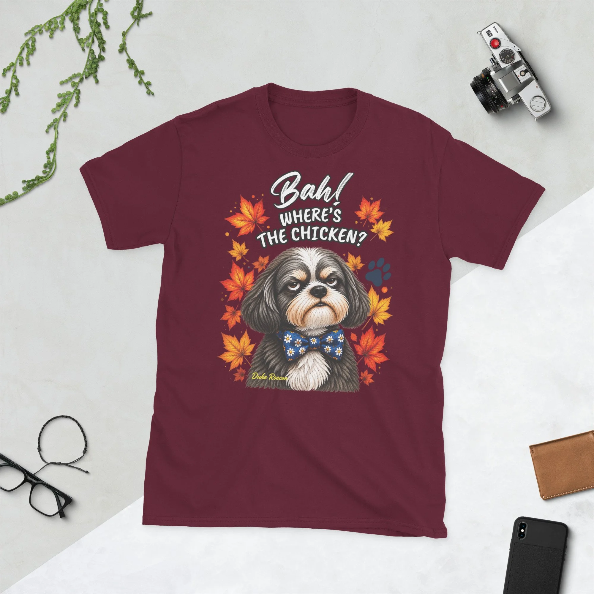 Bah! Where's the Chicken? Duke Roscoe Tee in maroon, flat lay: grumpy Shih Tzu in a blue bow tie amid autumn leaves