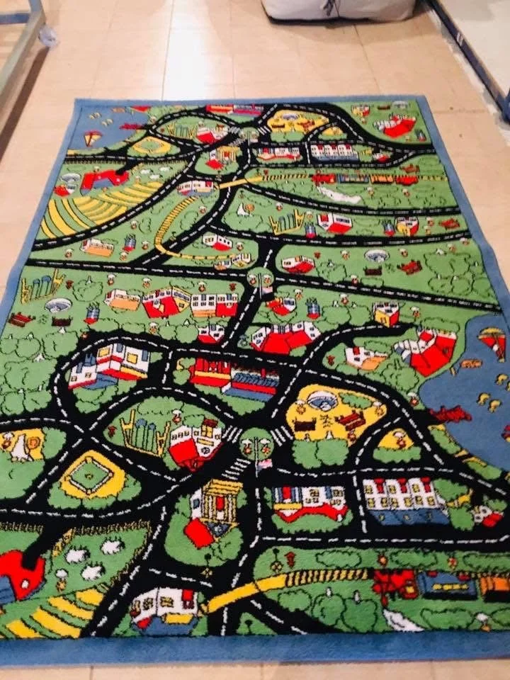 Colorful children's play rug with a neighborhood map design, showcasing roads, houses, and various landmarks.